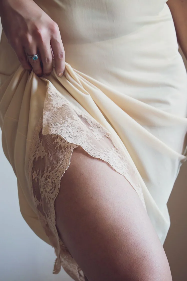 Bridal boudoir detail shot with white lace lingerie in natural window light at Cincinnati photography studio