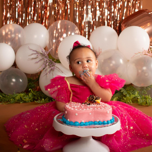 Baby girl in a pink dress at a 1st birthday cake smash representing the planning step for booking at Say Yes to Jess Cincinnati