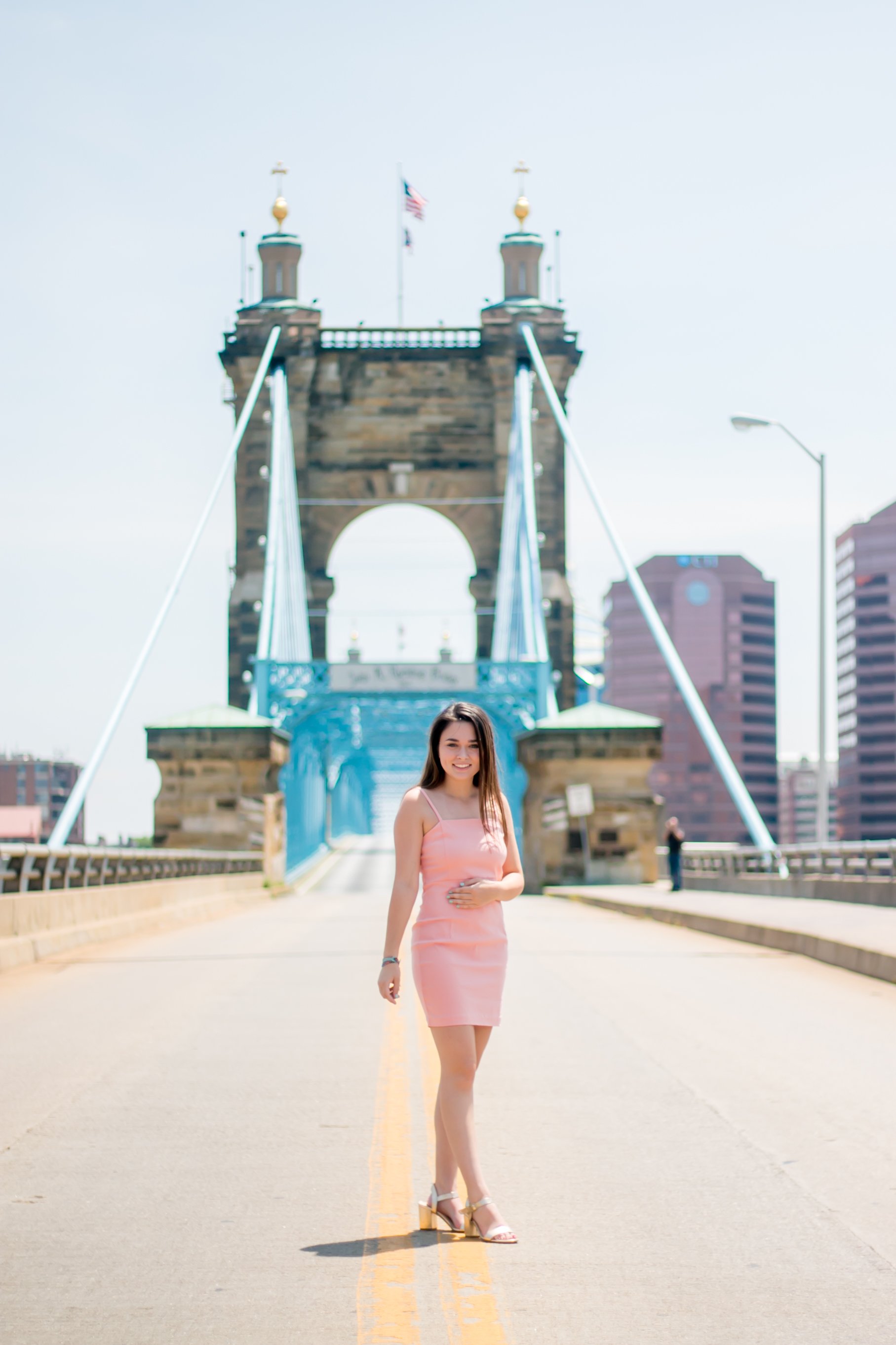 Senior portrait of girl in pink dress posing on the Roebling Suspension Bridge in Cincinnati Ohio