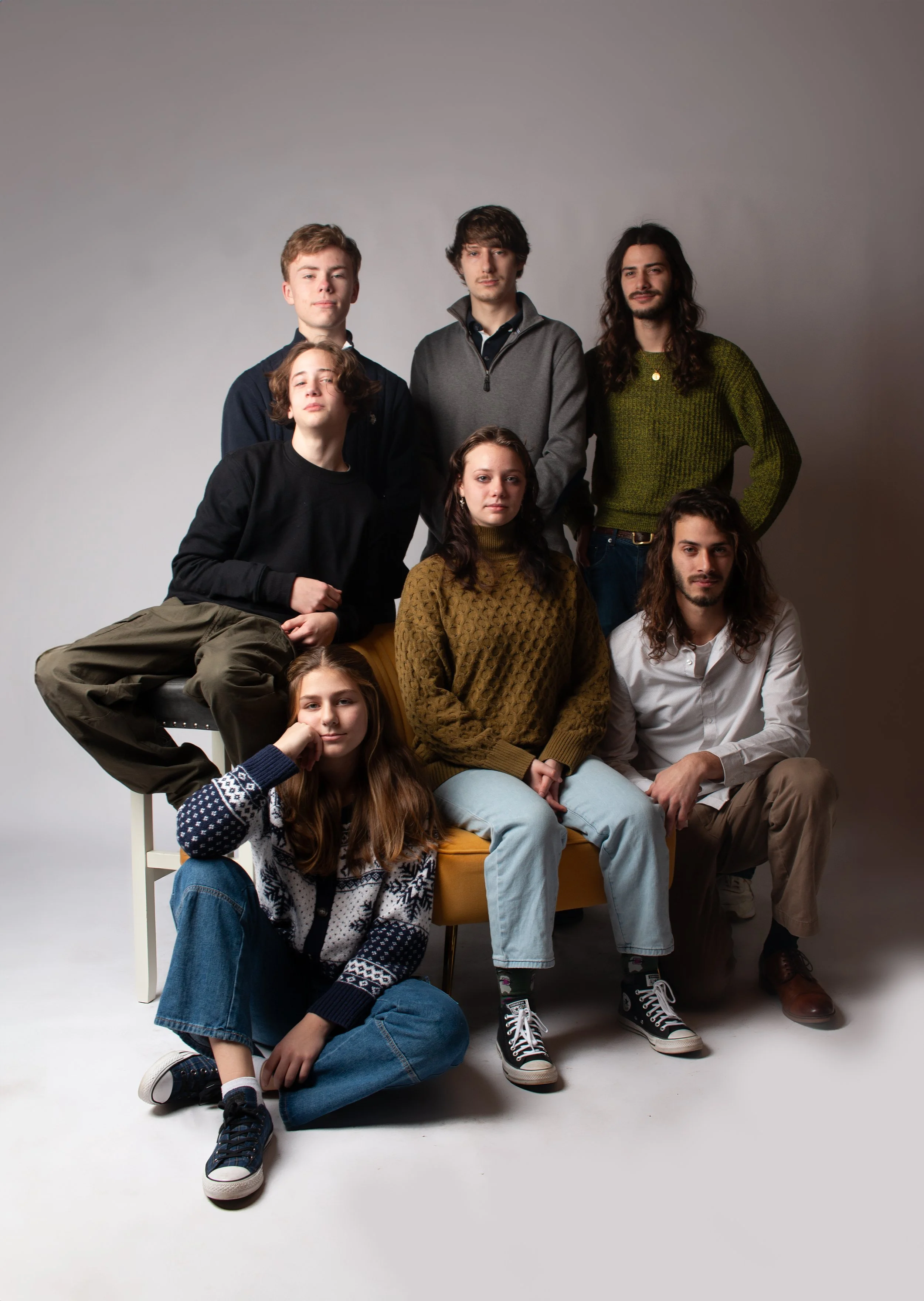 Group of six young adults in casual earth tone outfits posing together during a family portrait session at Say Yes to Jess Cincinnati studio