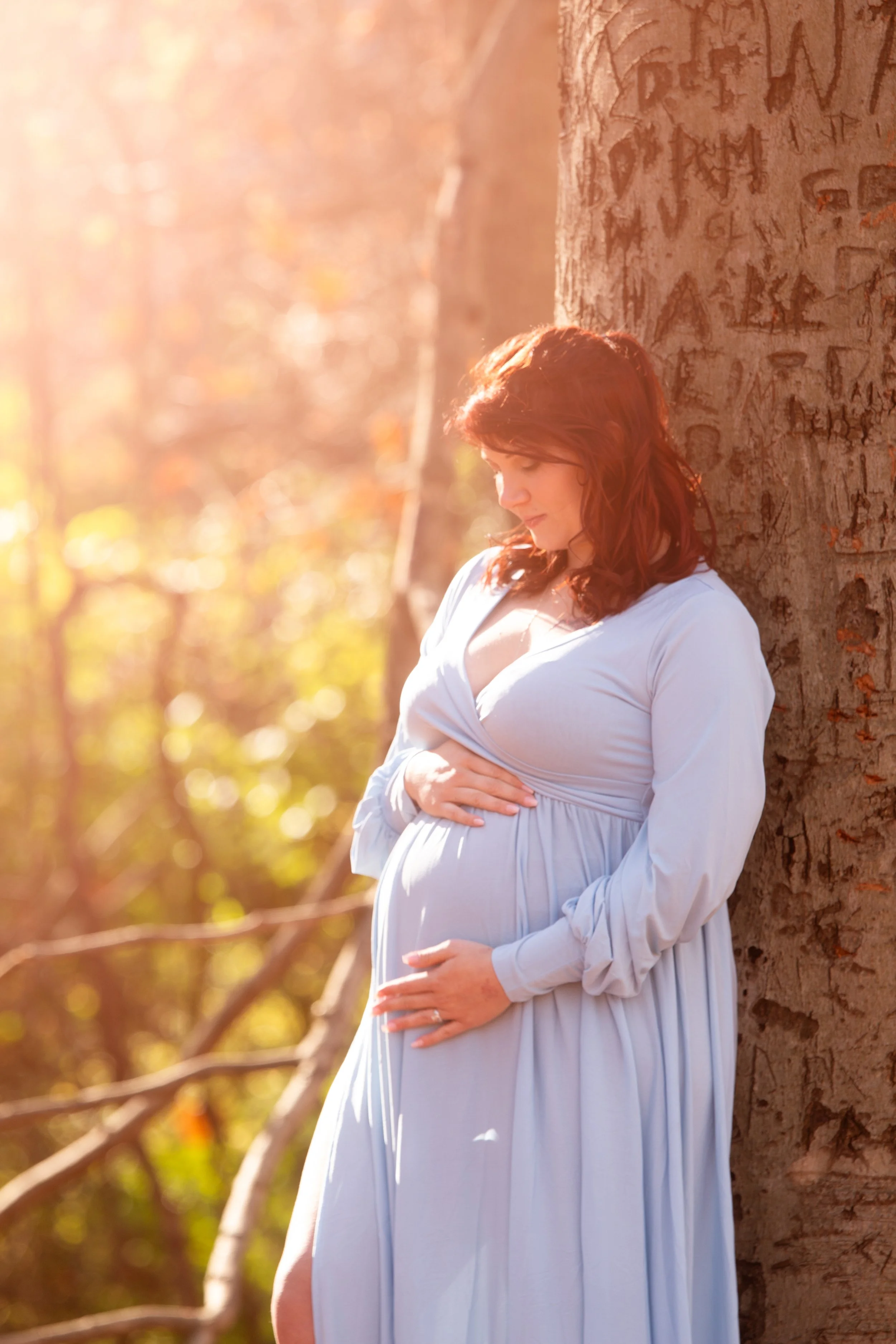 Golden hour maternity portrait of pregnant woman backlit by sunlight during outdoor pregnancy photoshoot