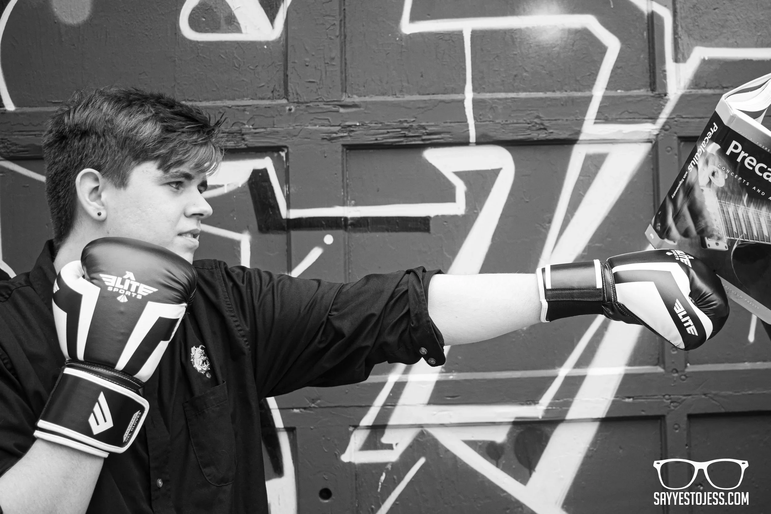 Senior photo session with boy punching his least favorite class pre calc book
