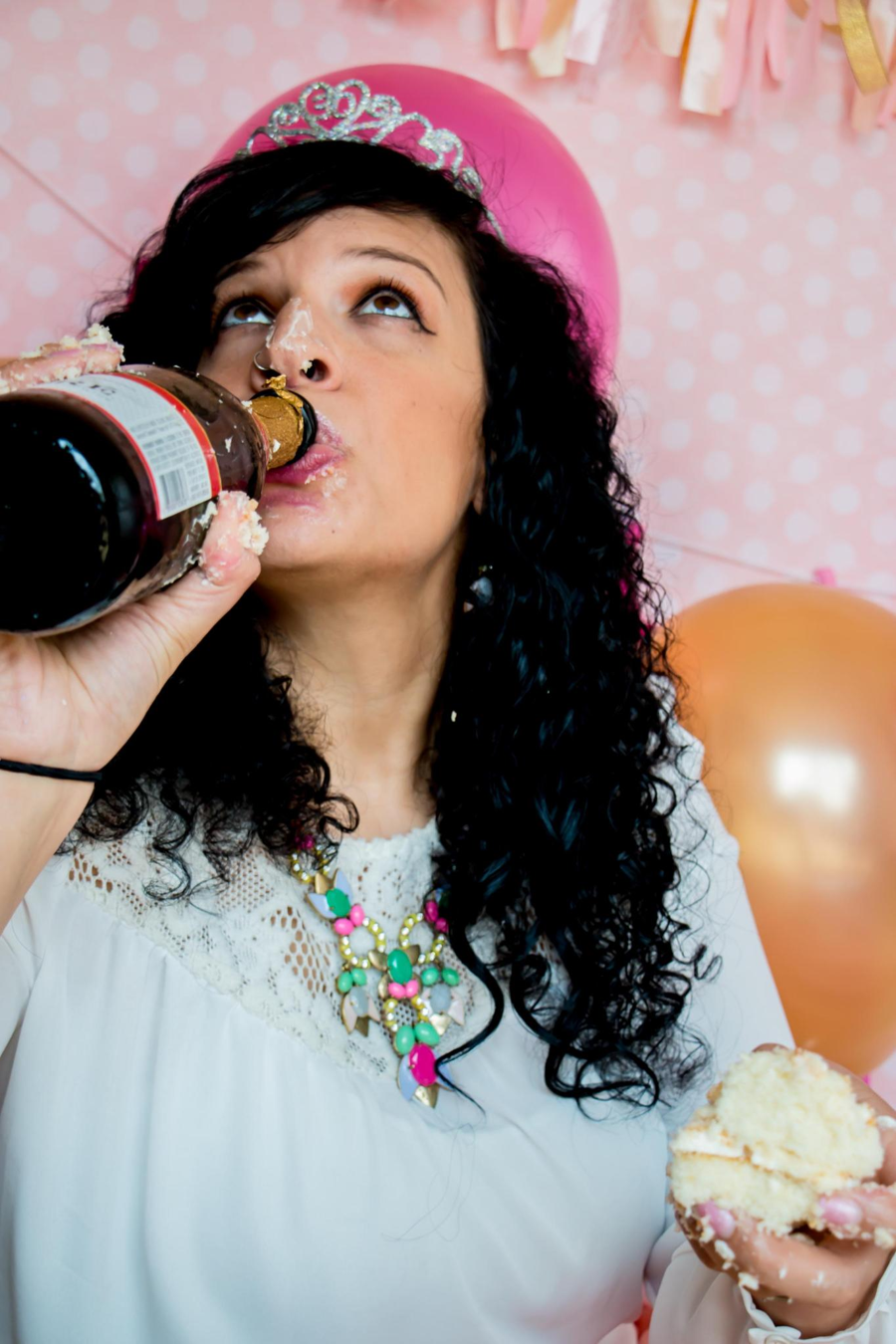 Woman in a pink birthday crown eating frosting during an adult cake smash photoshoot in Cincinnati