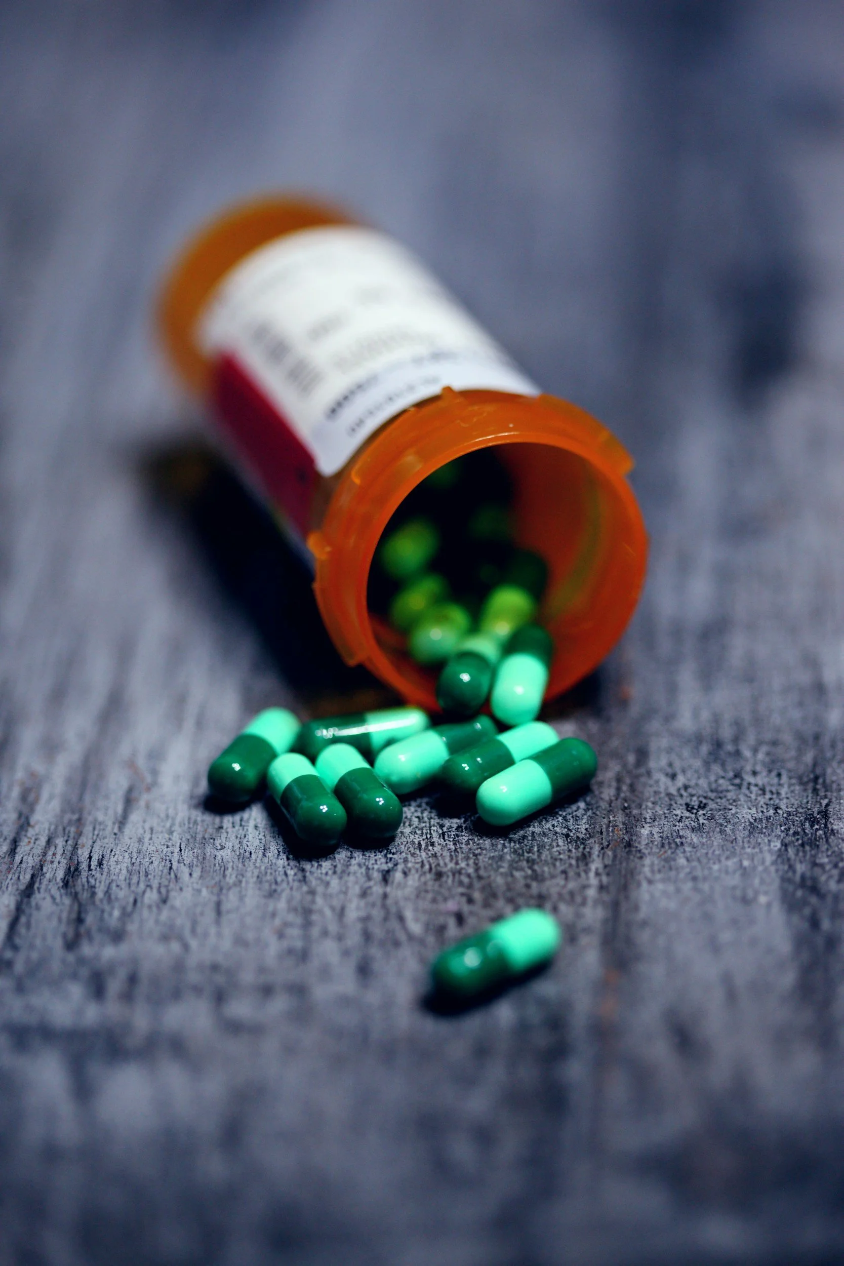 Bottle with pills spilling out on a gray background