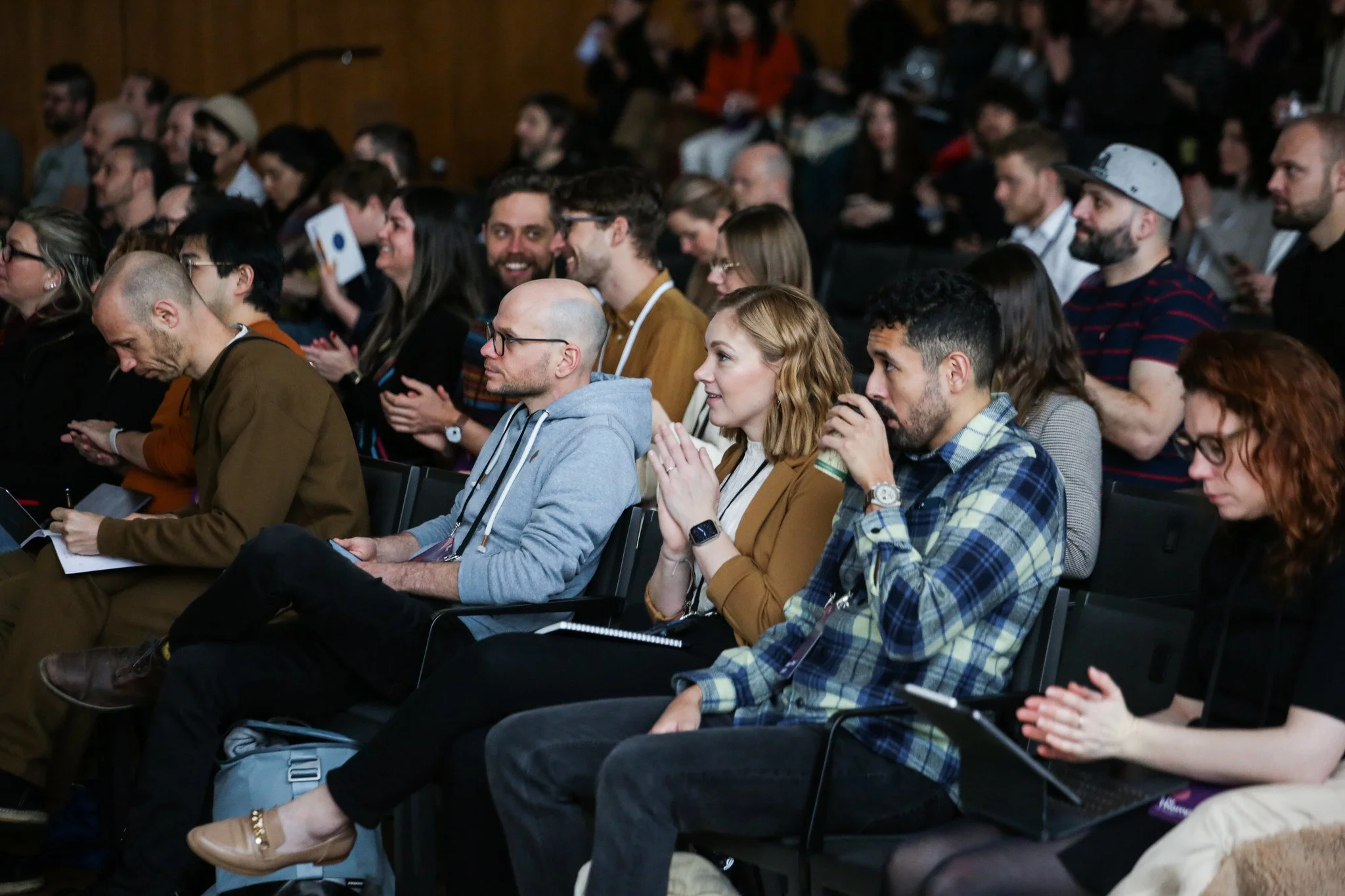 Audience members sitting and listening at an indoor conference or event.