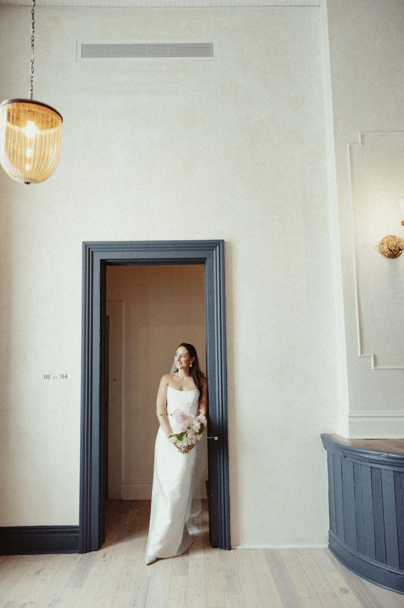 Bride peering out of a window at hotel peter and paul