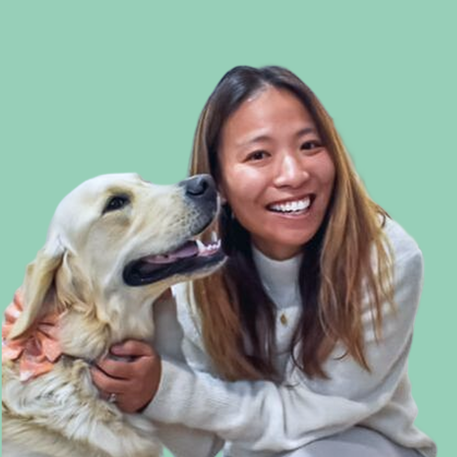 A woman with long brown hair smiling next to a golden retriever dog against a green background.