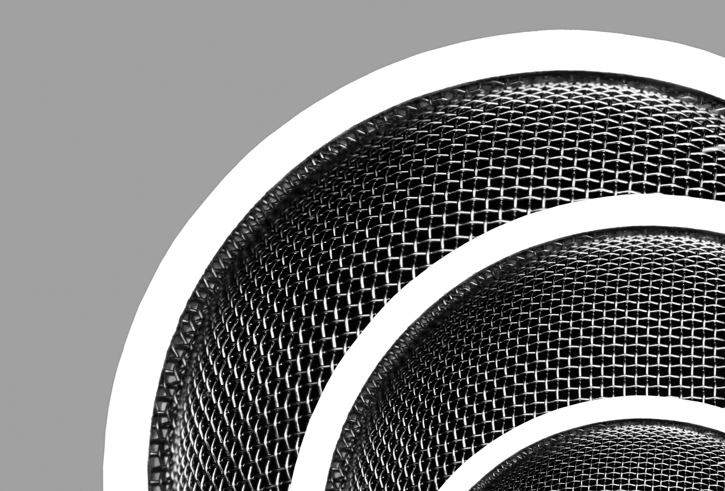 Close-up of a black metal mesh speaker grille with white curved lines overlaying the top and bottom.
