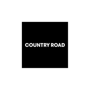 A sign with the words "COUNTRY ROAD" in purple on a white background, set against a purple background.