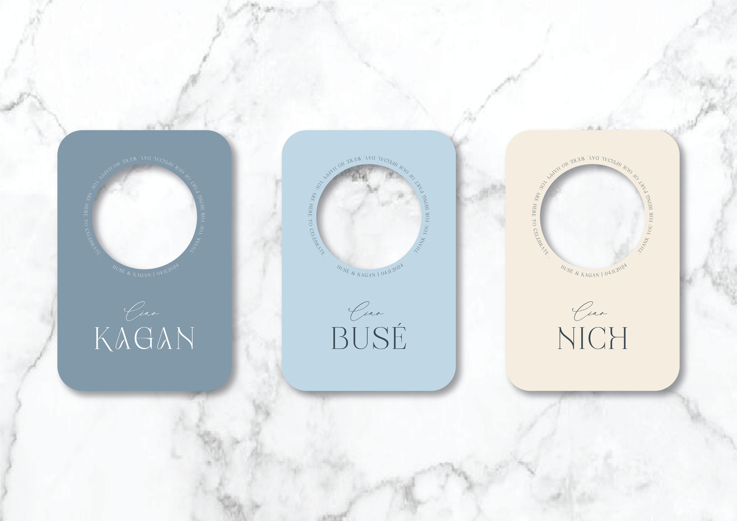 Three door hangers on a marble surface. The hangers are labeled "KAGAN," "BUSÉ," and "NICH," each in a different color and featuring decorative typography.