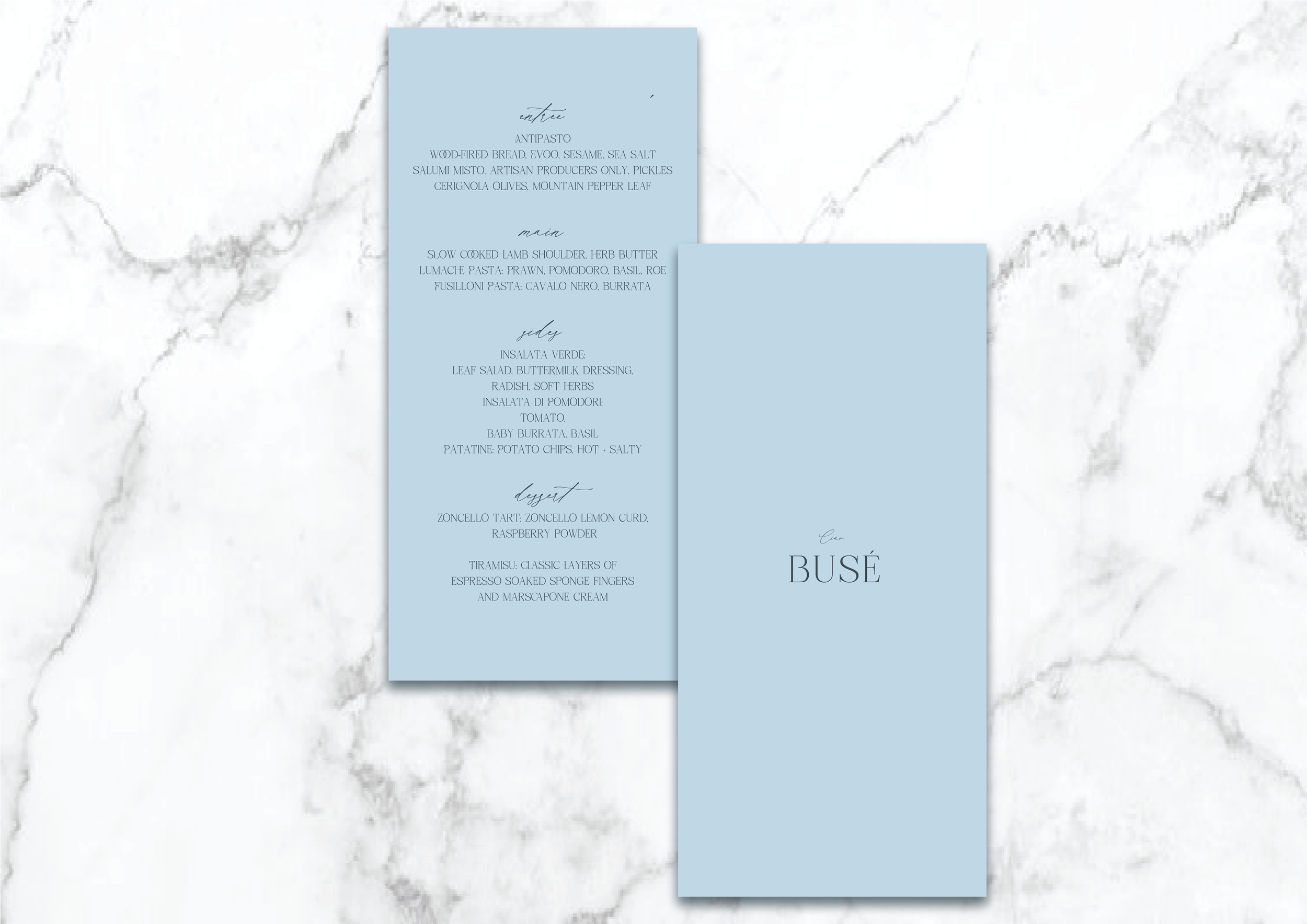 Two light blue restaurant menus on a marble surface. The left menu lists courses: entree, main, sides, and dessert, featuring items like antipasto, slow-cooked lamb shoulder, insalata verde, and tiramisu. The right menu displays the name "Busé."