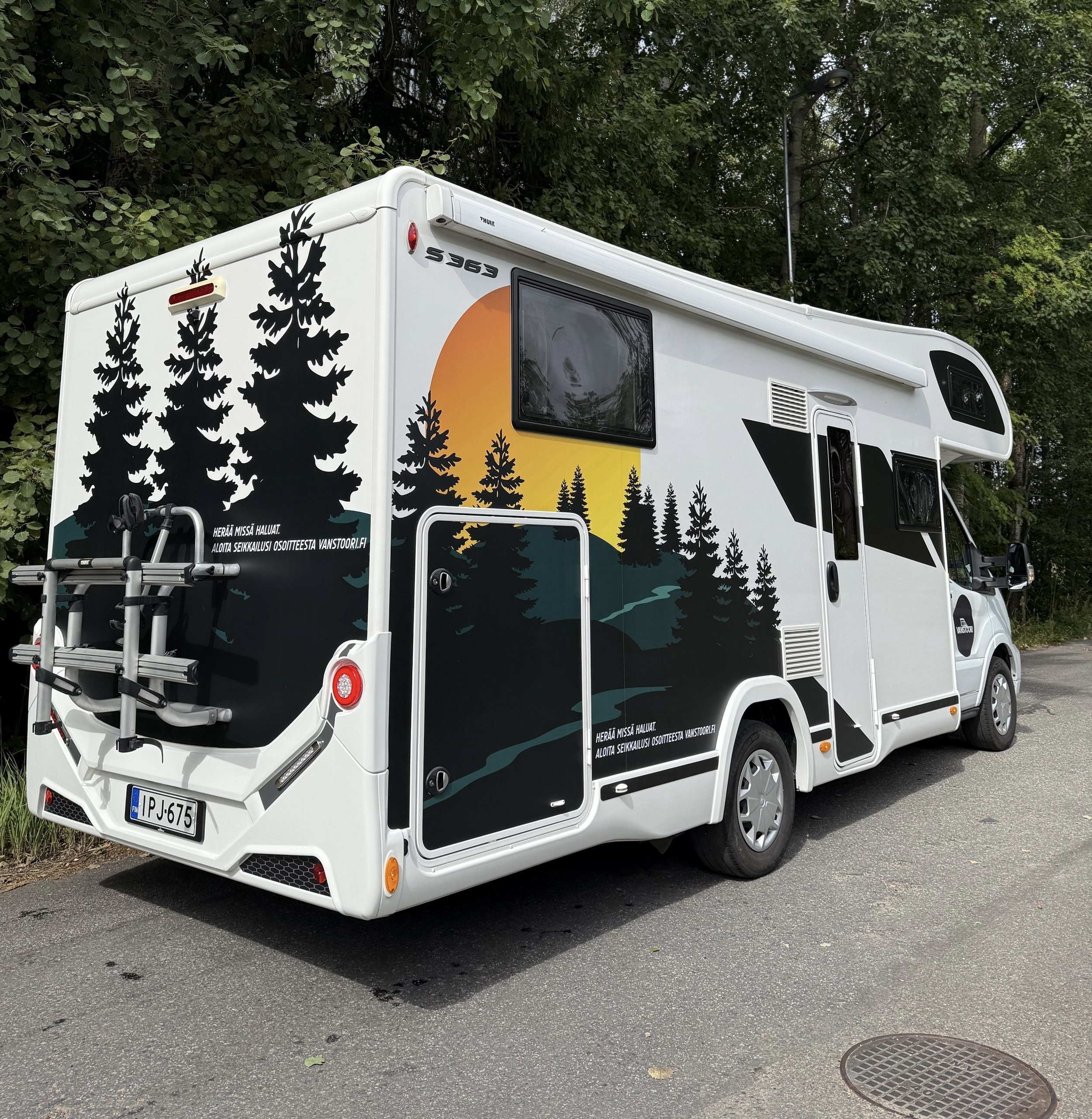 Matkailuauto, jossa Vanstoorin mainosteipit.