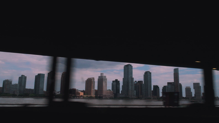 City skyline view of tall buildings seen through a window or opening with a dark ceiling or overhang at the top of the image.
