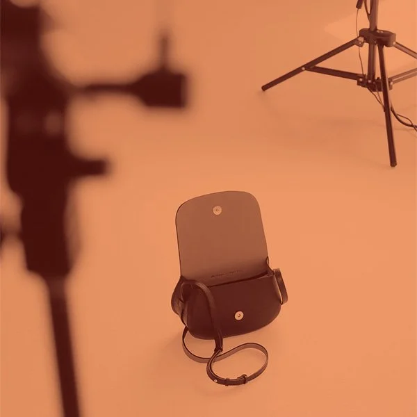 Eine offene Tasche auf einem Boden in einem Fotostudio mit Stativ im Hintergrund.