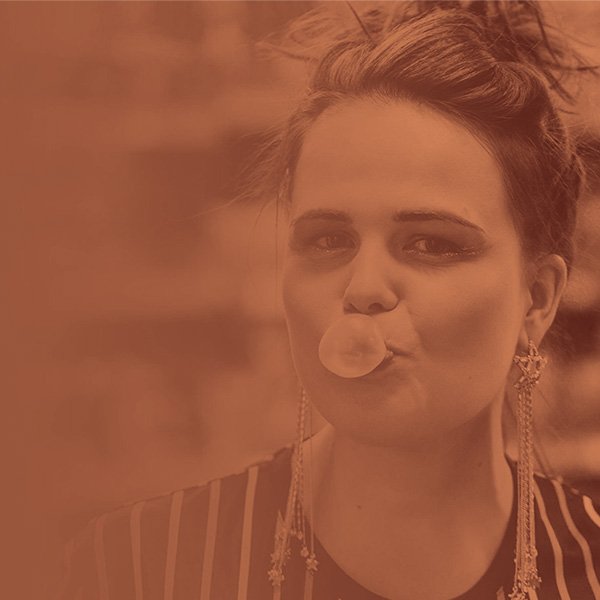 Frau bläst einen Kaugummiballon, mit langen Ohrringen und gestreiftem Oberteil. Sepia-Farbschema.