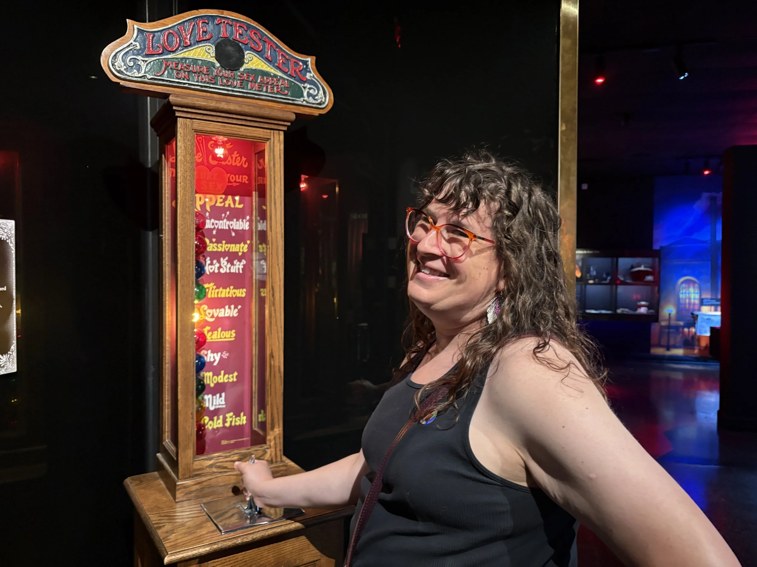 A photograph of author Sylvie Althoff using an antique "love tester" machine at the New Orleans Storyville Museum, earning a middling sex appeal score of "lovable".
