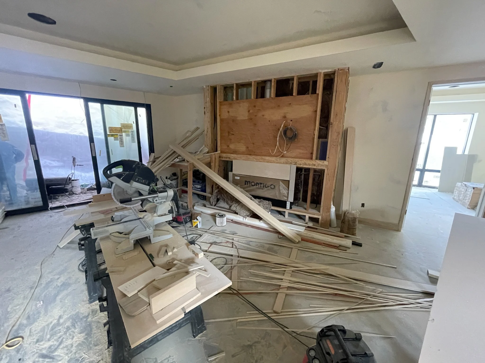 Interior of a house under renovation with construction tools, materials, and partially built wall frame.