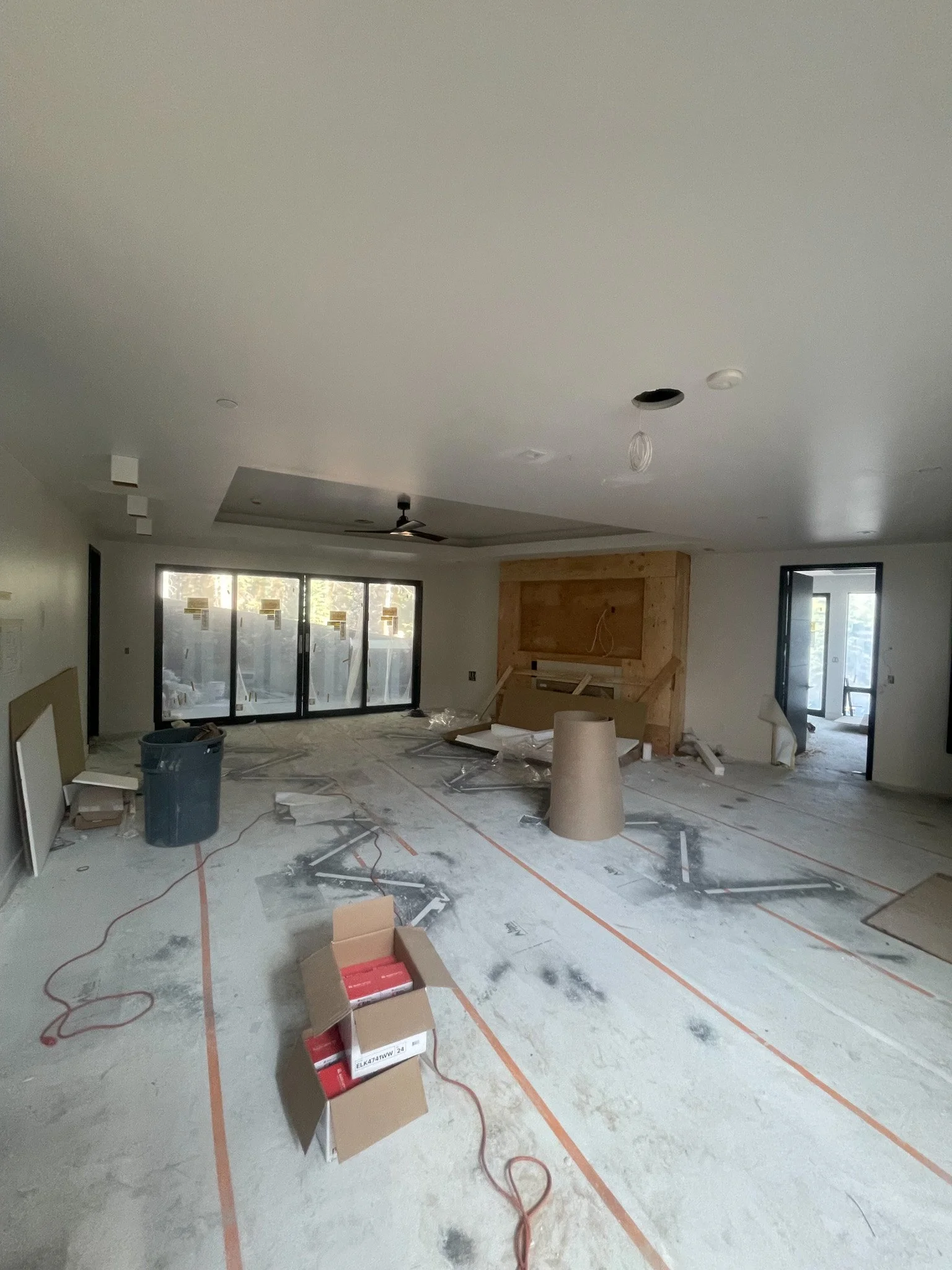 Interior of a room under construction with tools, cardboard boxes, and construction debris on the floor.