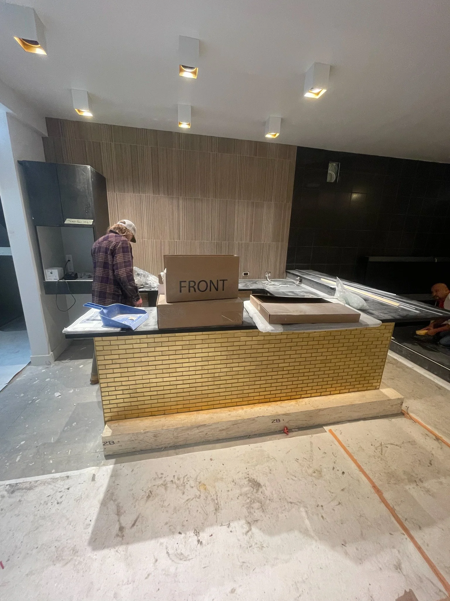 Construction site with a counter covered in boxes, a person working, and construction tools and materials visible.