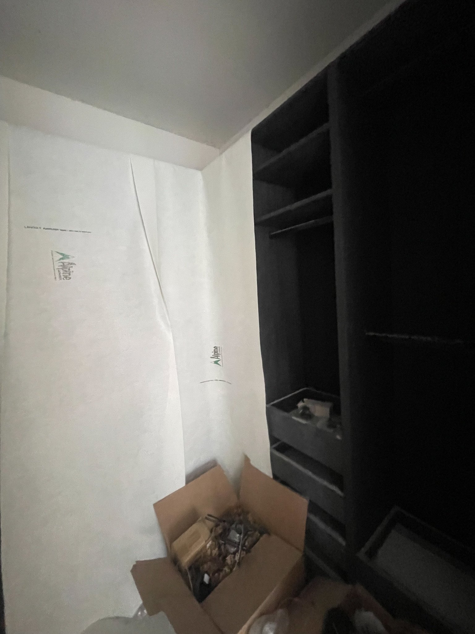 Empty black shelving unit in a room with a cardboard box on the floor.