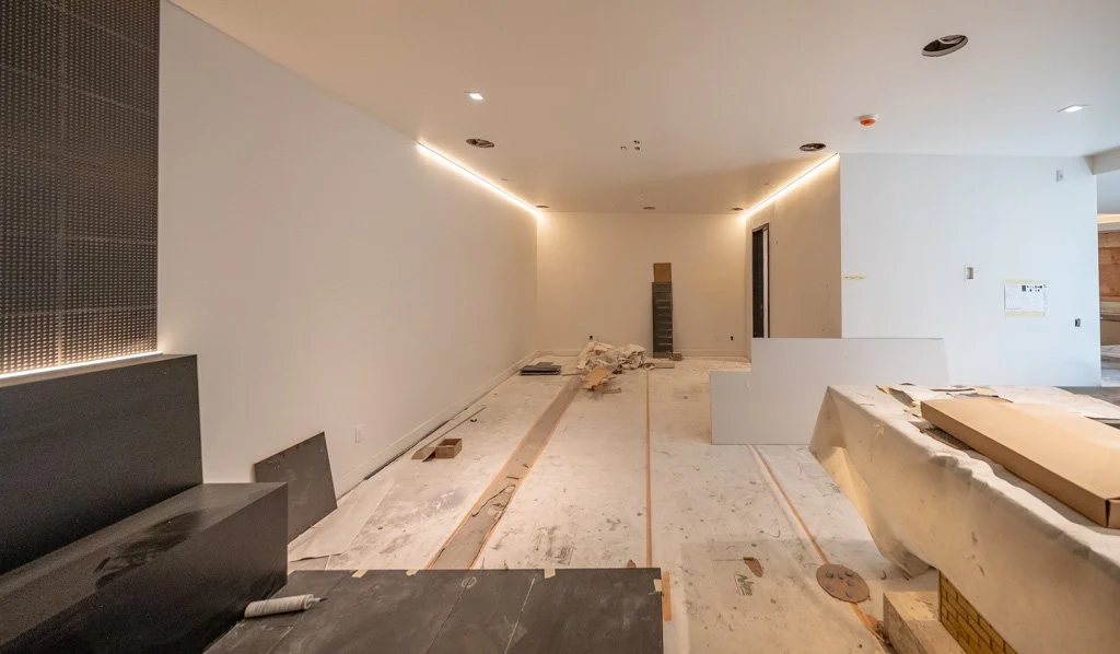 Interior of a room under construction with white walls, some construction materials, and a partially finished ceiling.