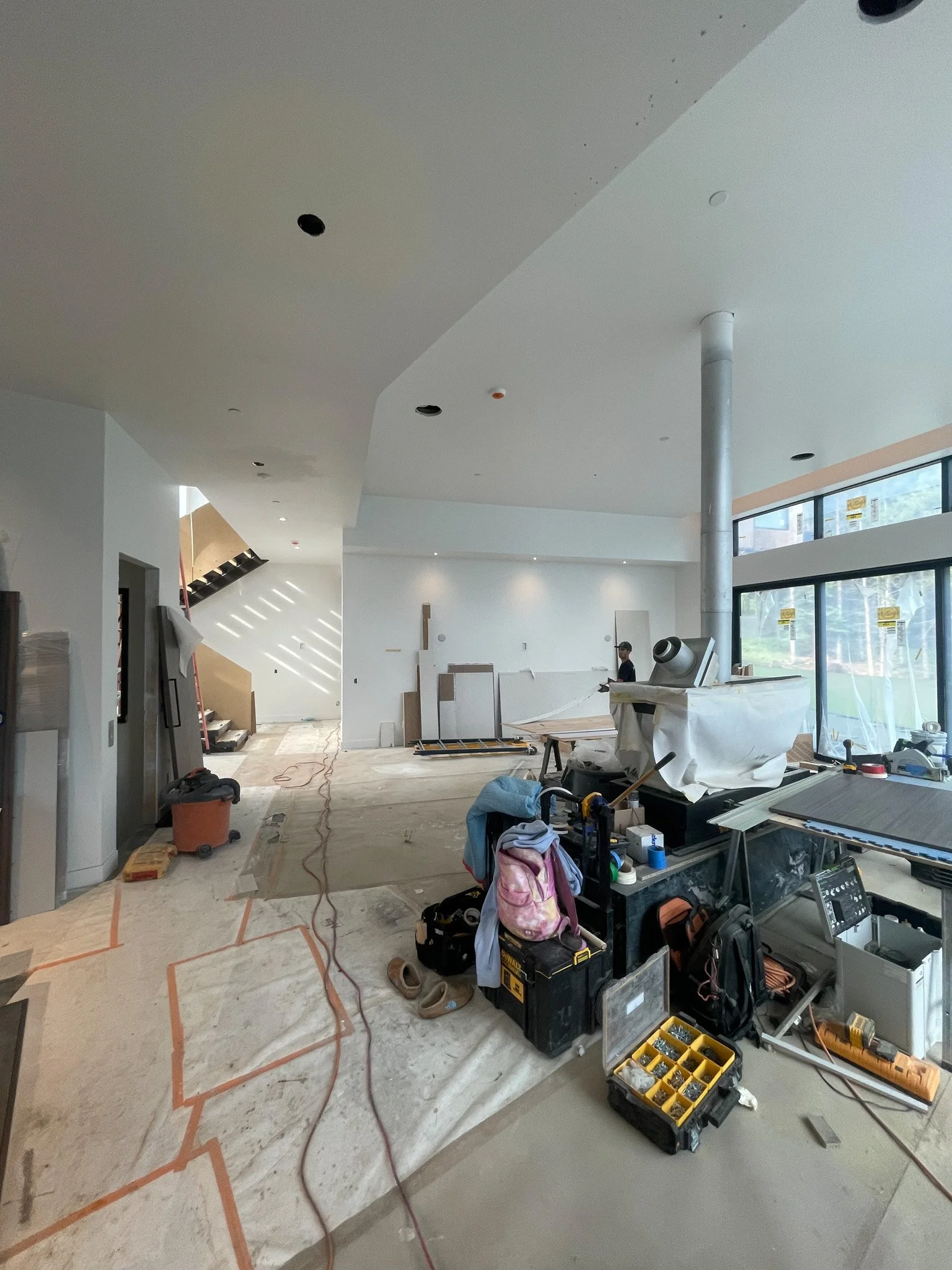 Interior of a building under construction, featuring unfinished walls, construction tools, and equipment scattered on the floor.