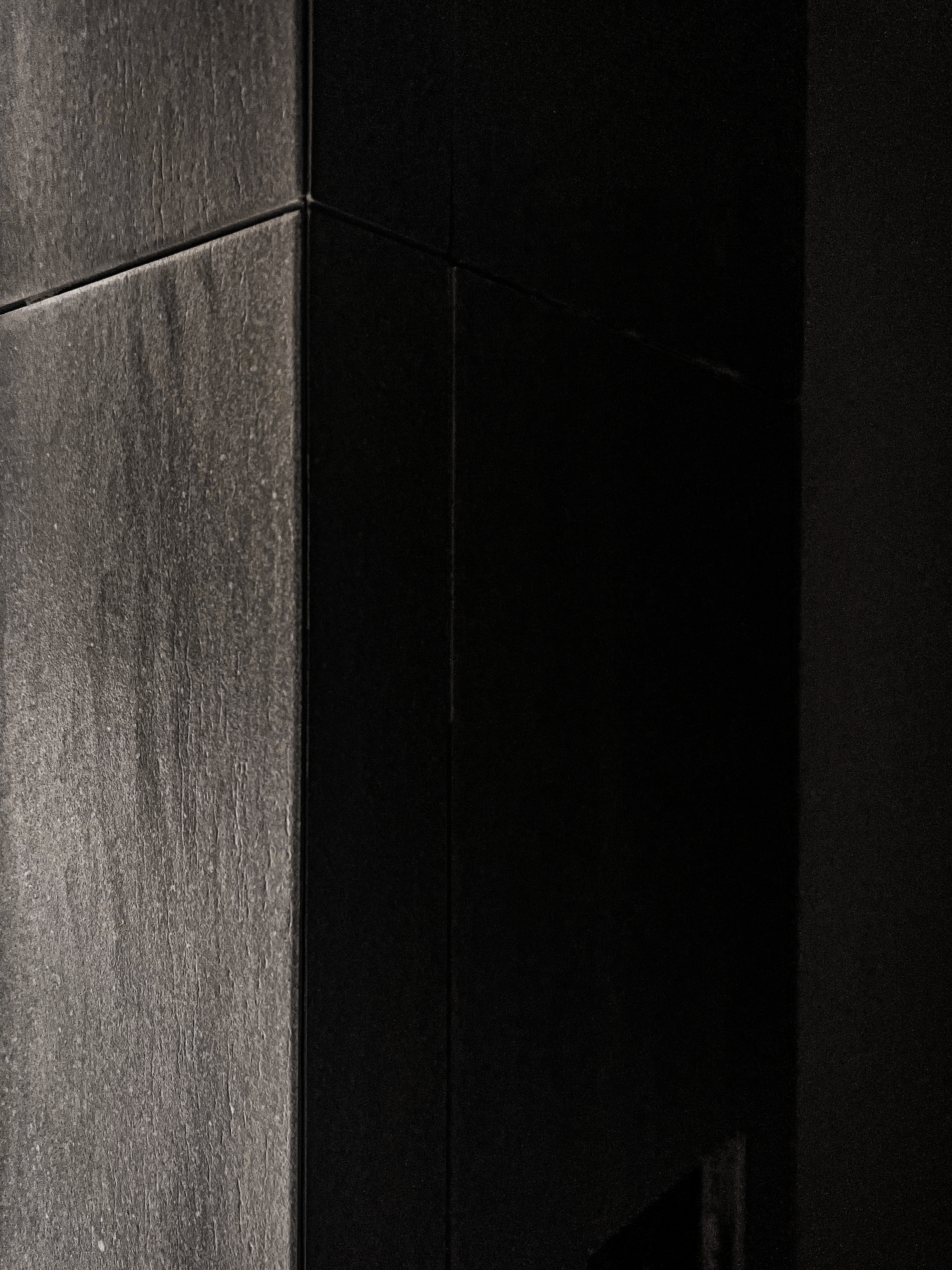 Close-up of a dark, textured wall with a tiled corner.