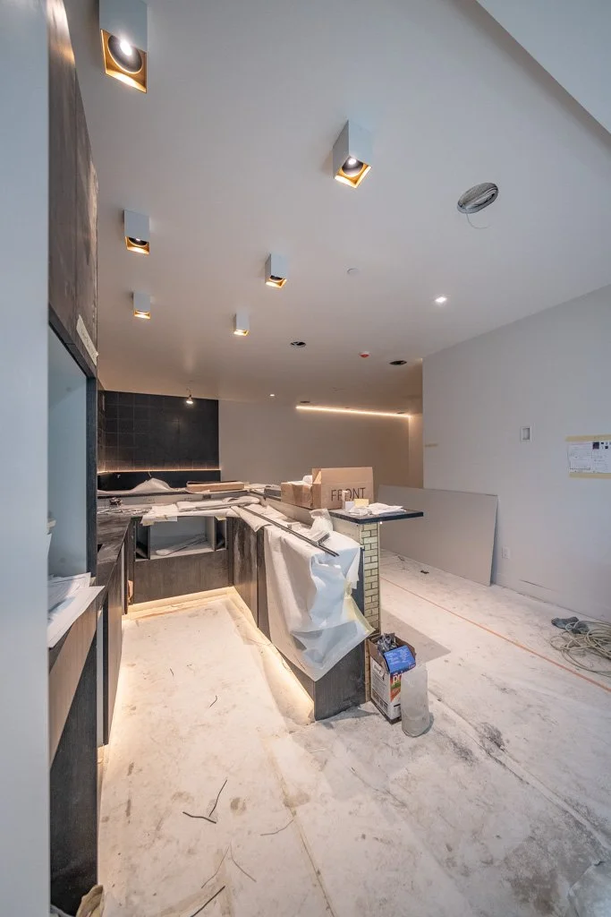 Under construction kitchen with unfinished floors, construction materials, and partially installed cabinetry and appliances.