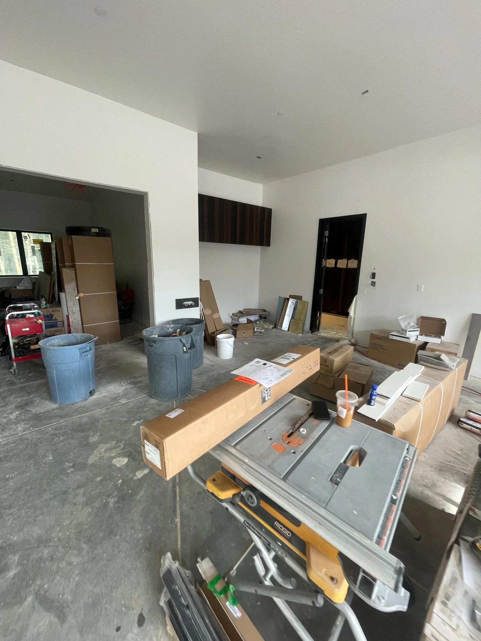 Interior of a house under construction with construction tools, equipment, and boxes scattered around.