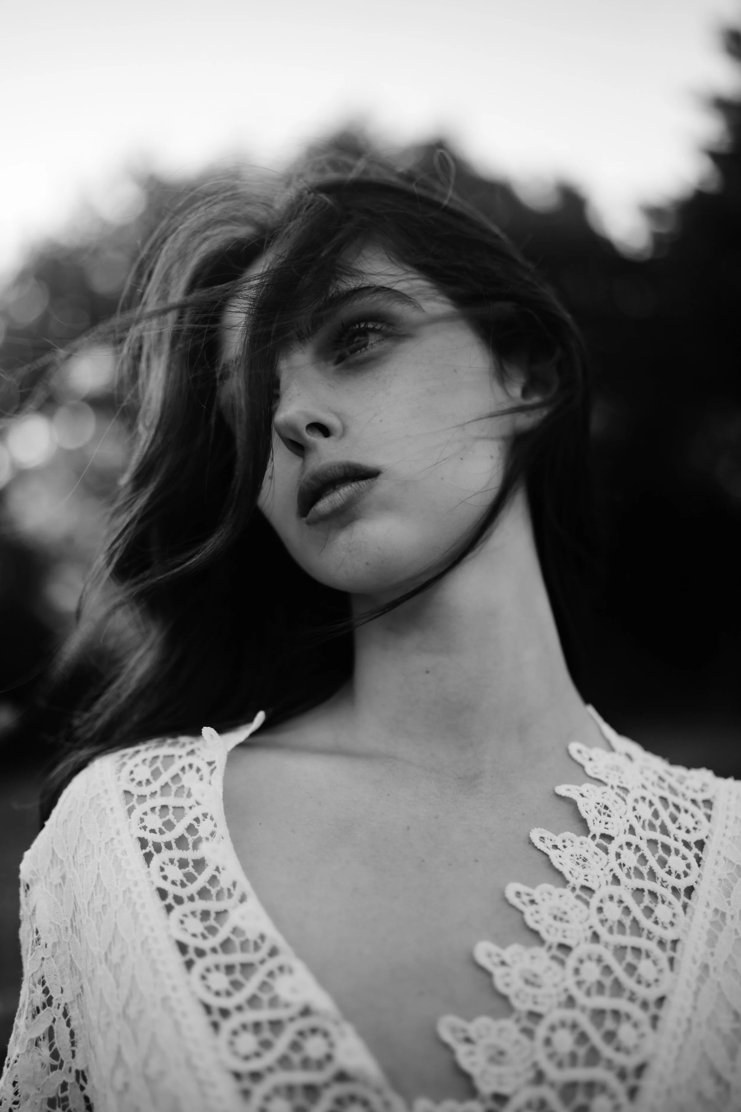Ragazza con capelli mossi e vestito di pizzo in bianco e nero, sguardo rivolto verso l'alto