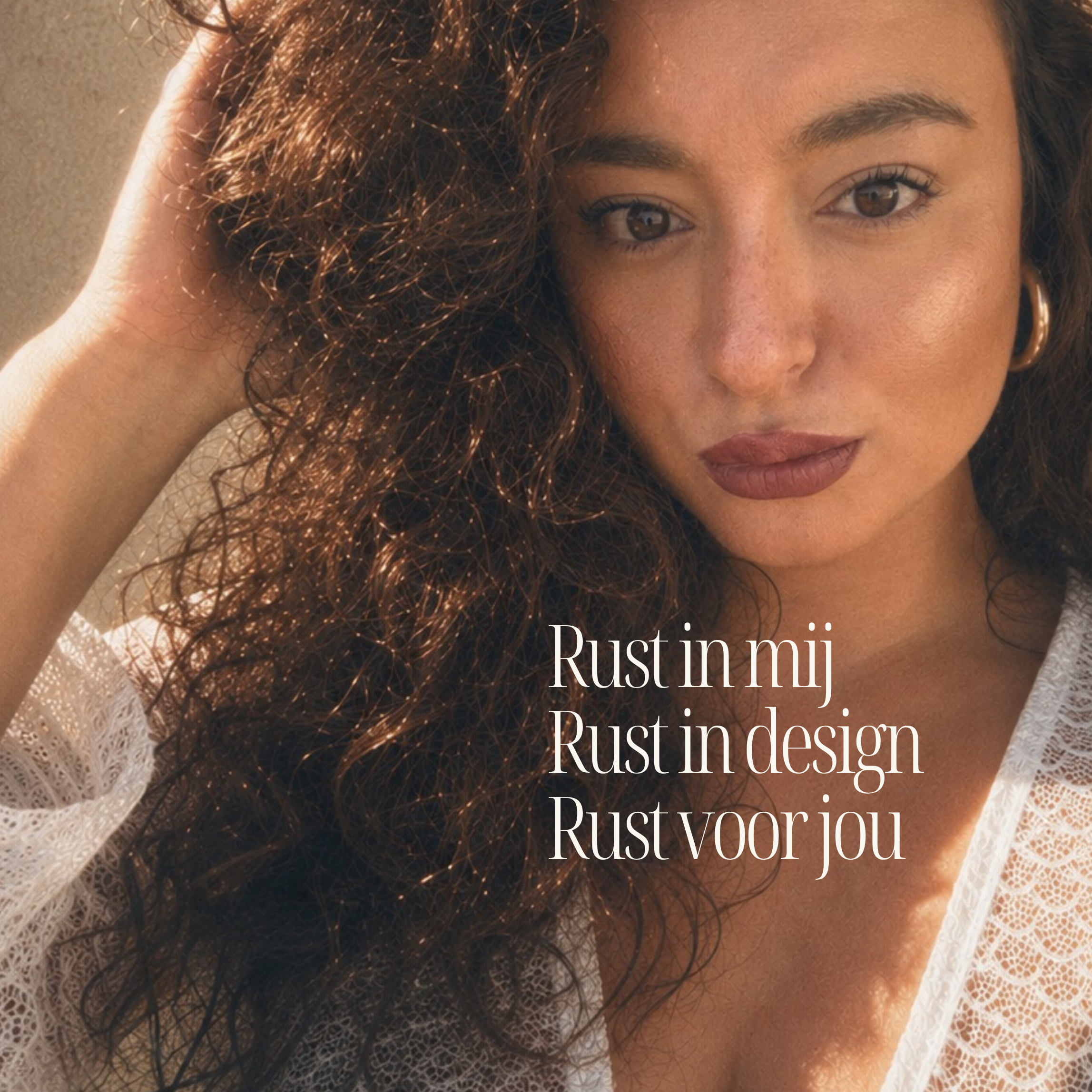 Close-up van een vrouw met kastanjebruine krullende haren, lichte huid en bruine ogen, die een witte kanten jurk draagt en in de camera kijkt.