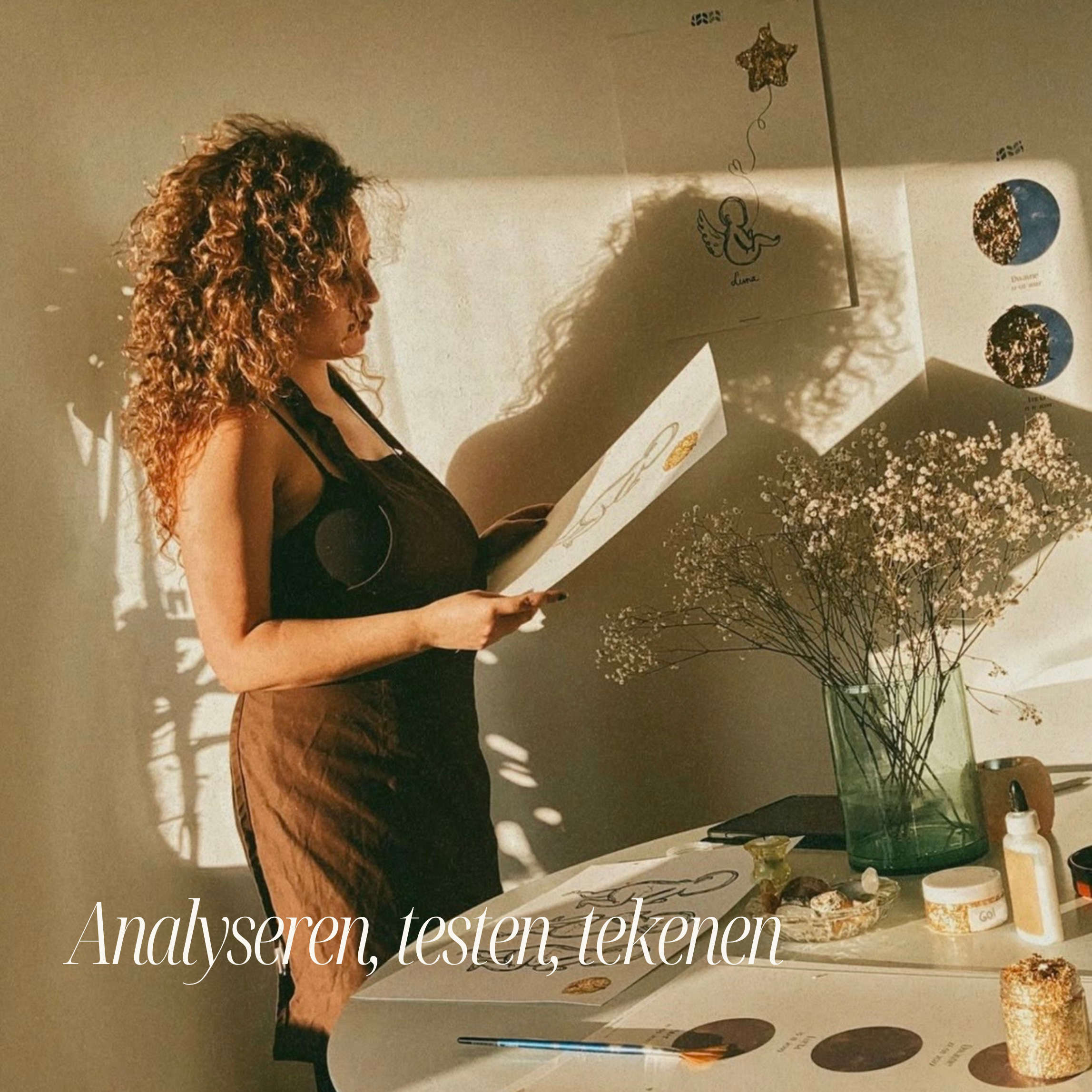 Een vrouw met lang, krullend haar leest een whiteboard, met decoratieve items en bloemen op de tafel eronder.