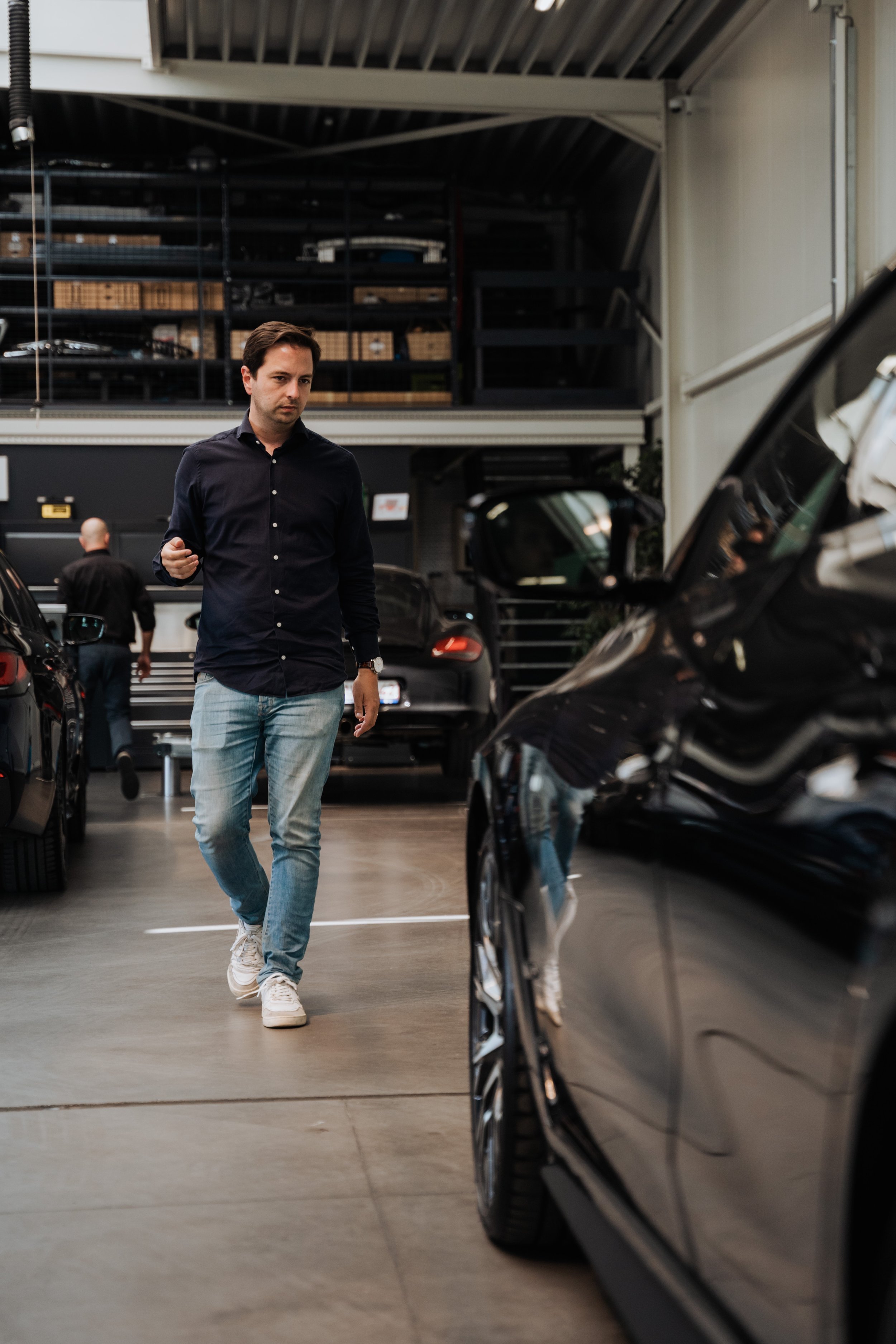Man loopt in een autowerkplaats tussen auto's.