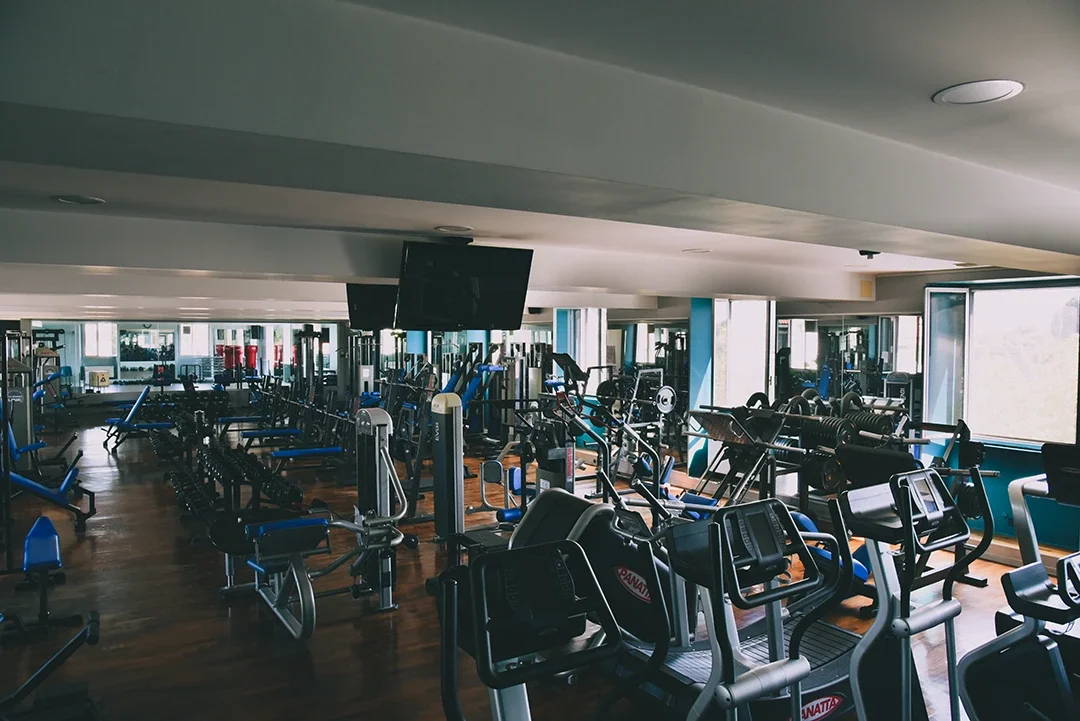 Palestra New Gold Gym a Vercelli: Palestra con attrezzi per esercizi, squat rack, e tapis roulant, illuminata da luce naturale tramite grandi finestre.