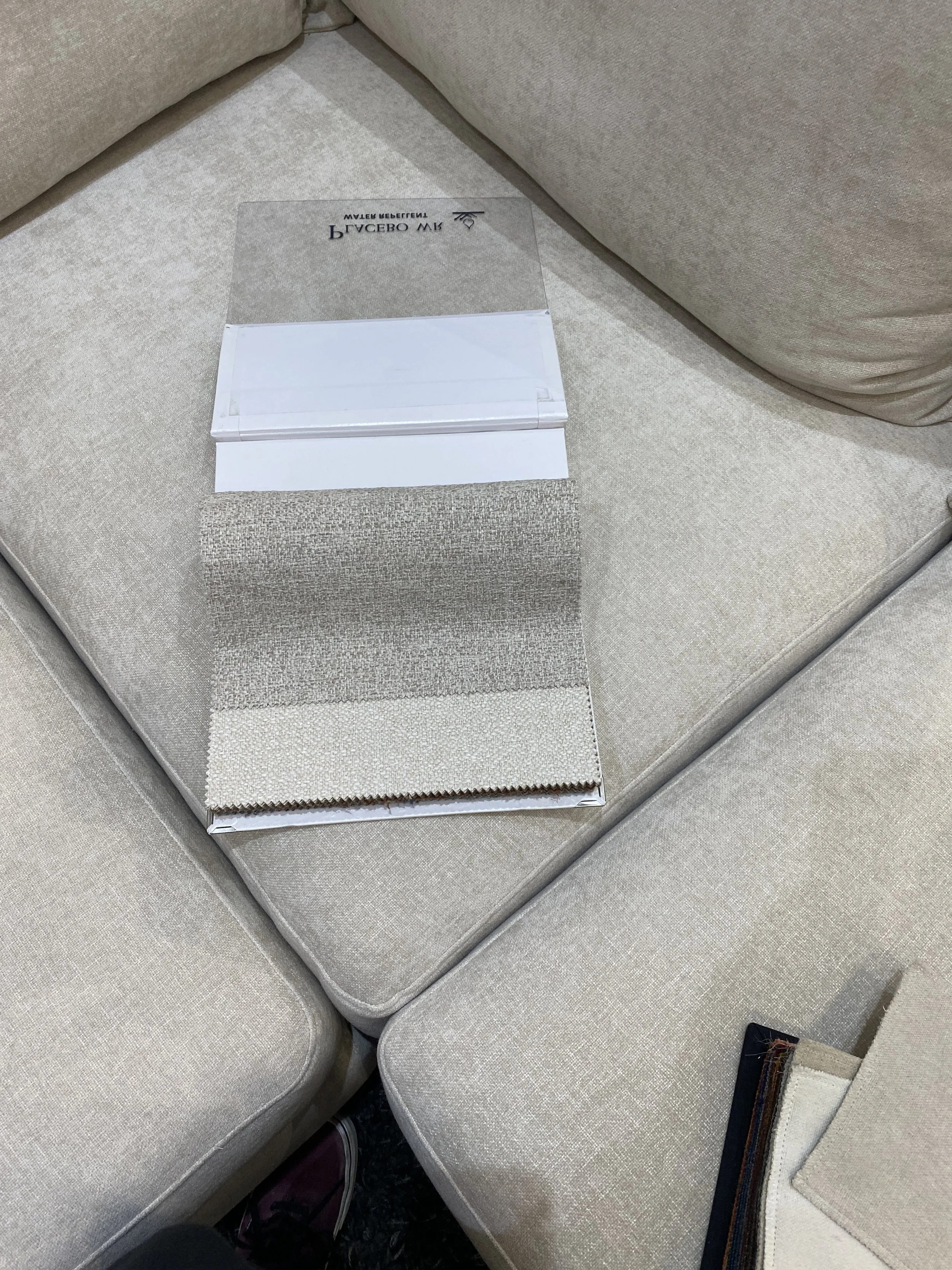 Fabric sample swatches and a color palette swatch on a beige sofa.