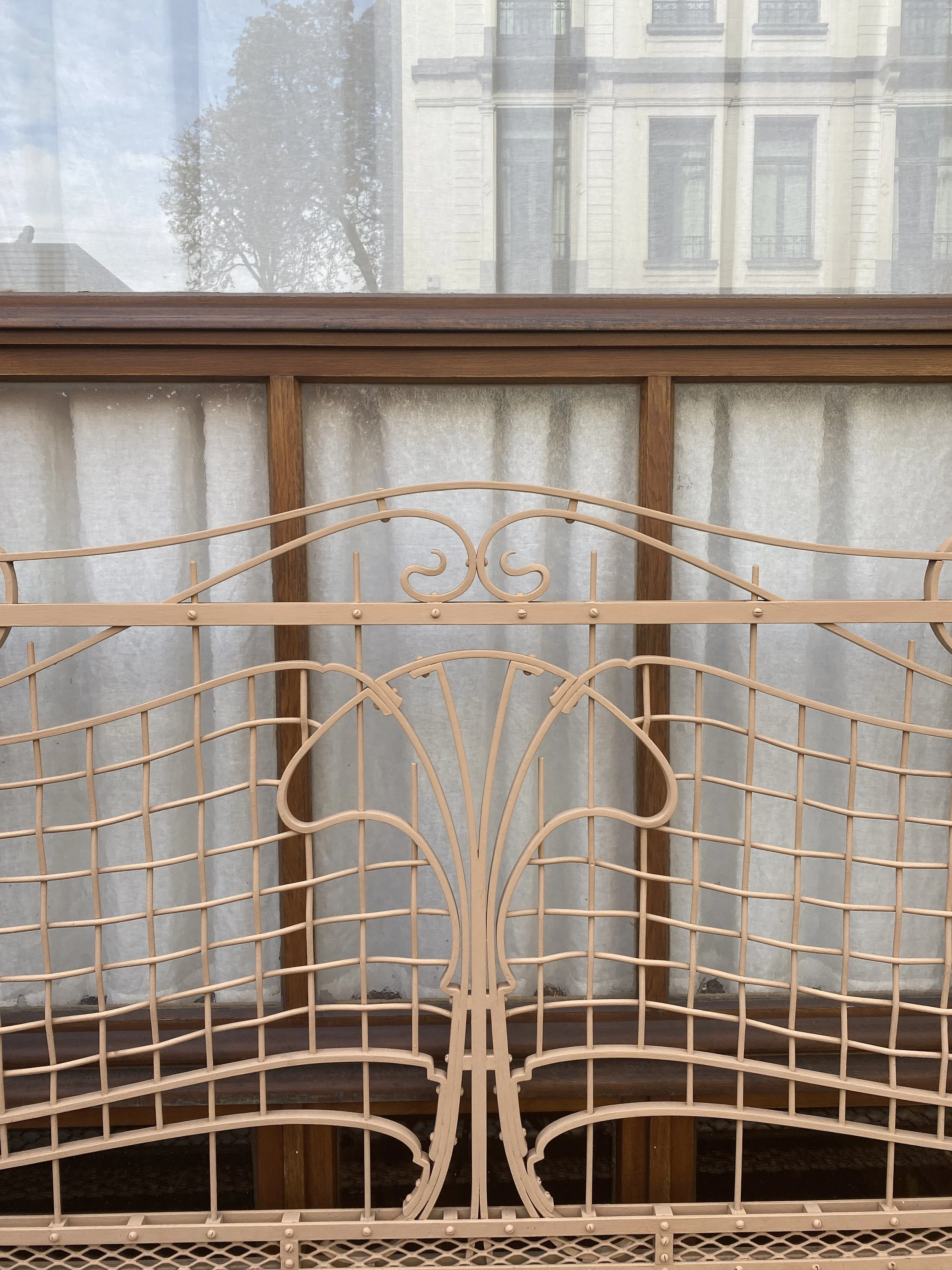 Decorative beige iron garden fence with intricate floral and geometrical designs.