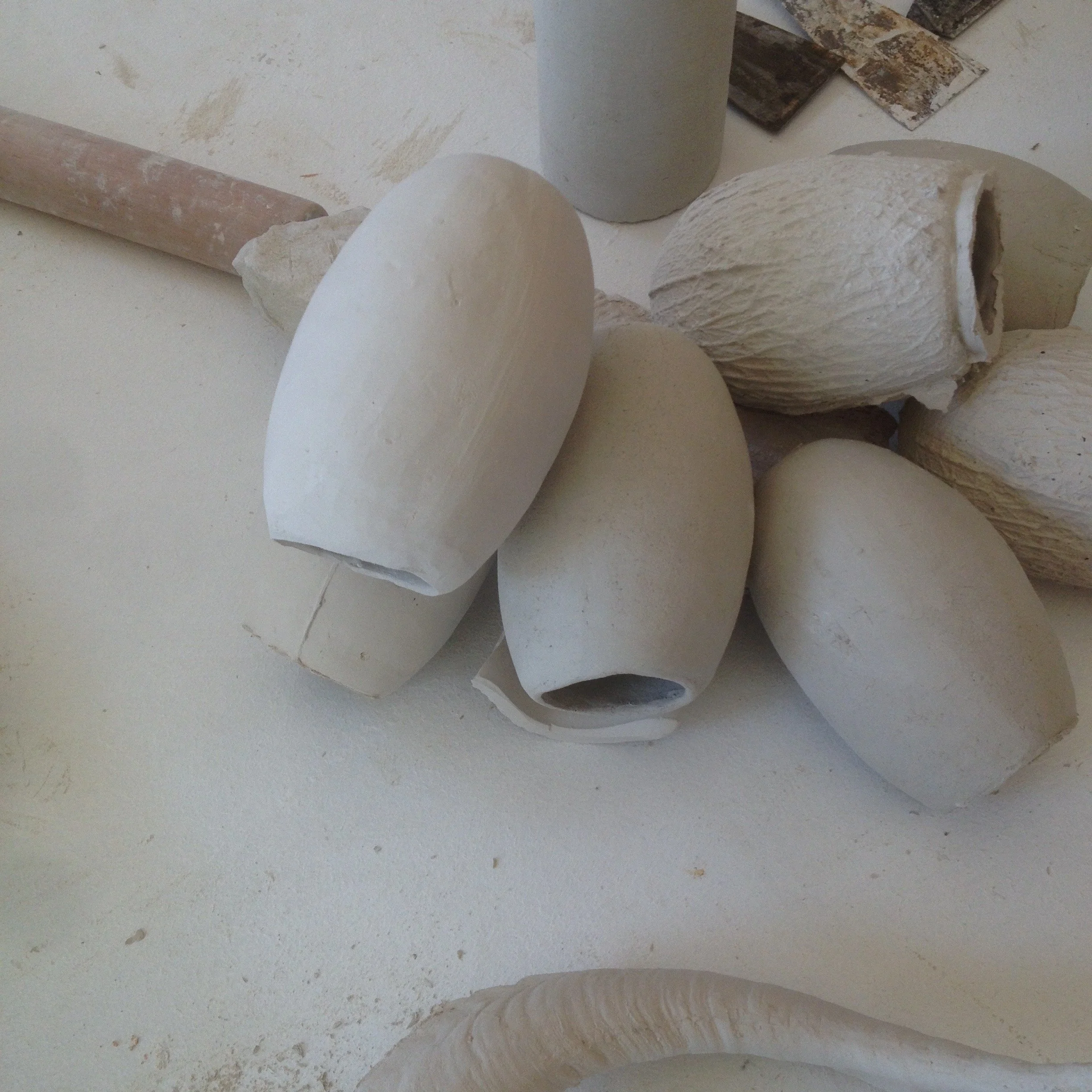 Several white ceramic or plaster molds and tools on a work surface, likely in an art or pottery studio.