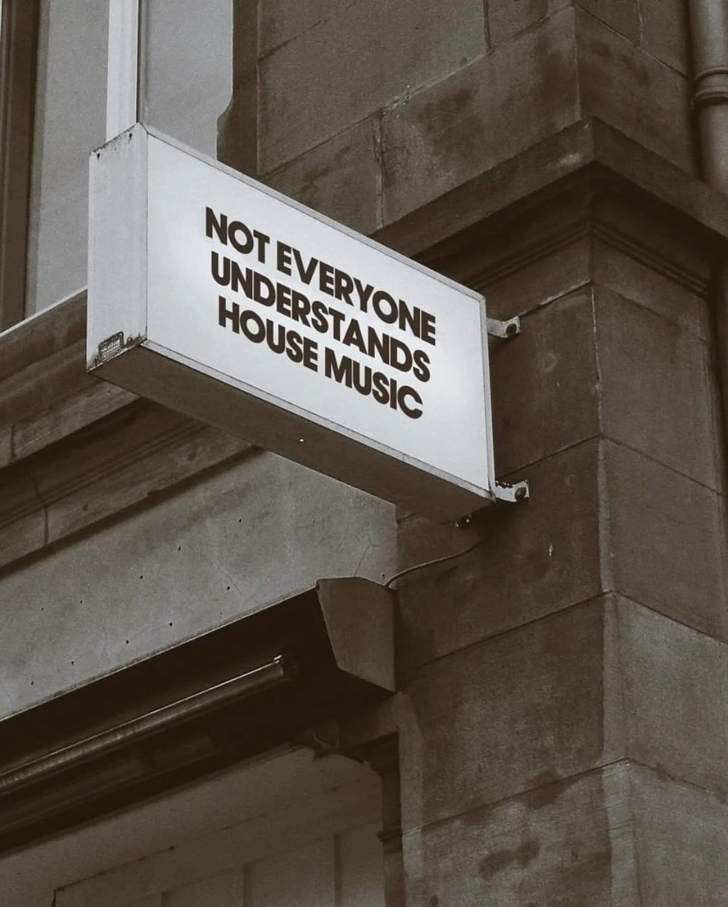 A street sign on a brick building reads 'Not Everyone Understands House Music'.