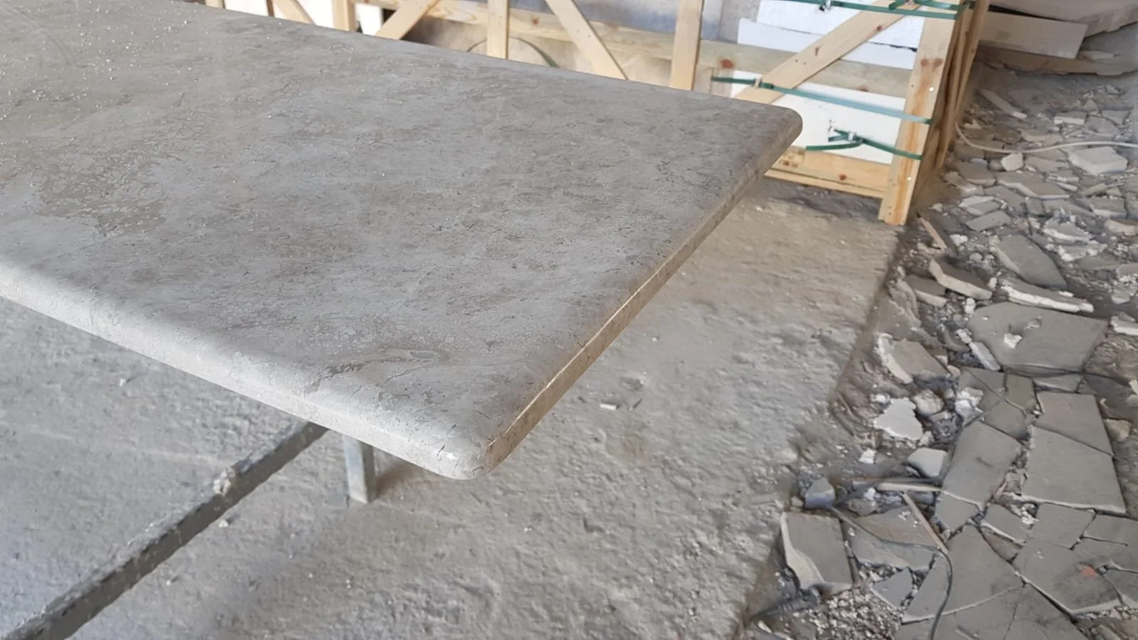Close-up of a granite countertop in a construction site with debris and wooden framing in the background.