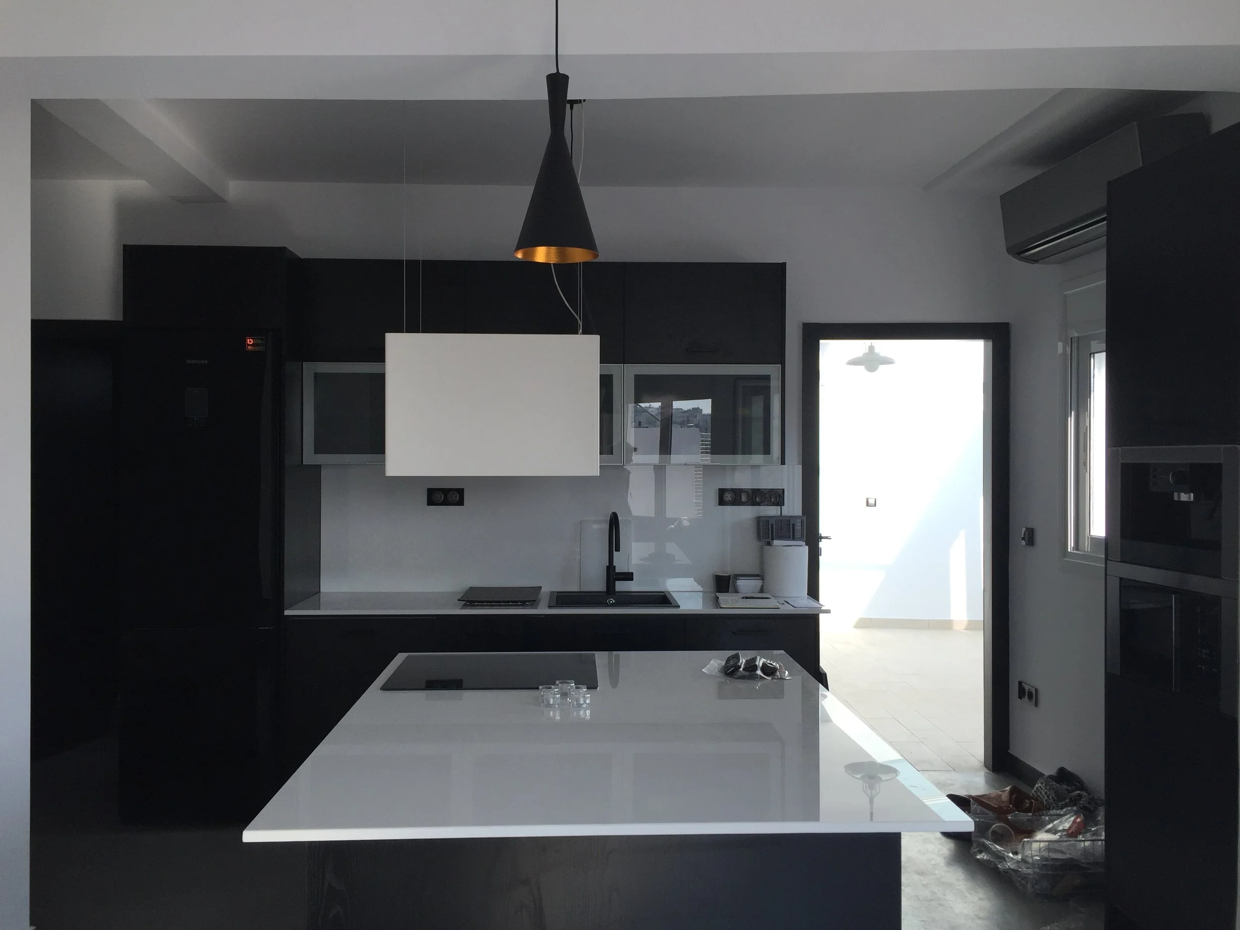 Modern kitchen with black and white color scheme, black cabinets, a white countertop, and large windows letting in natural light.