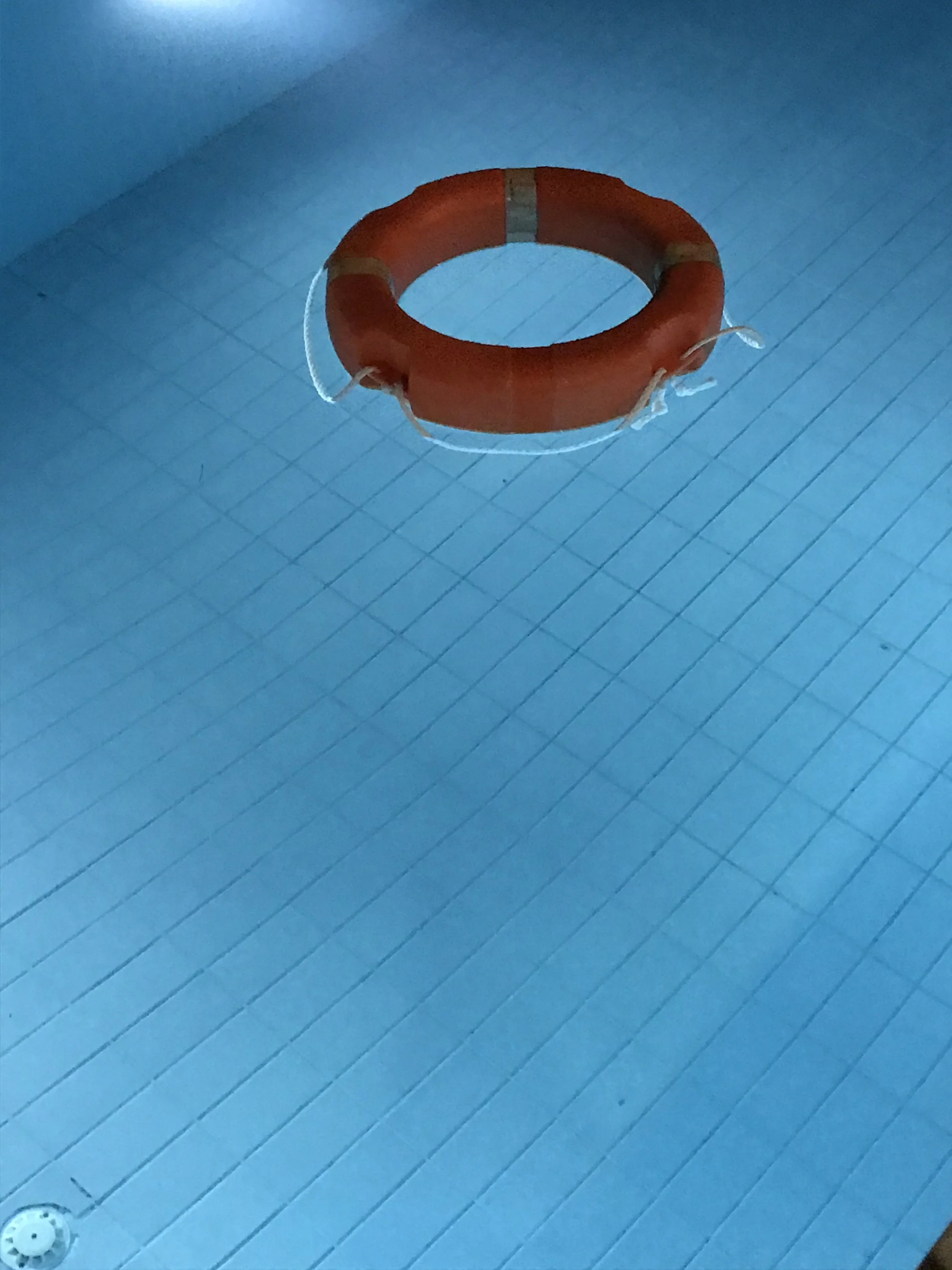 Orange life preserver floating in a swimming pool.