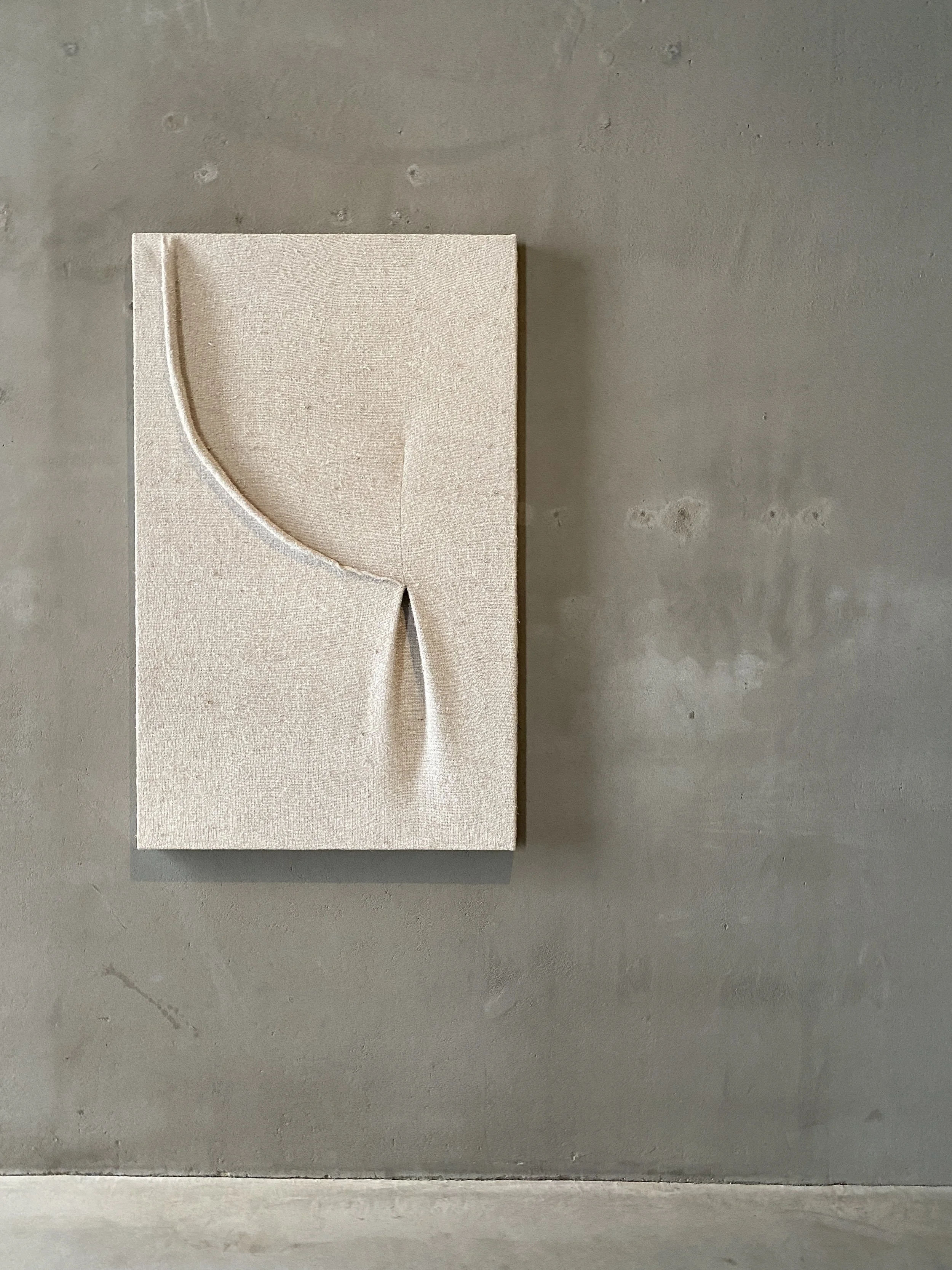 A beige or light-colored square object with a circular cutout in the upper left corner, placed on a gray concrete surface.