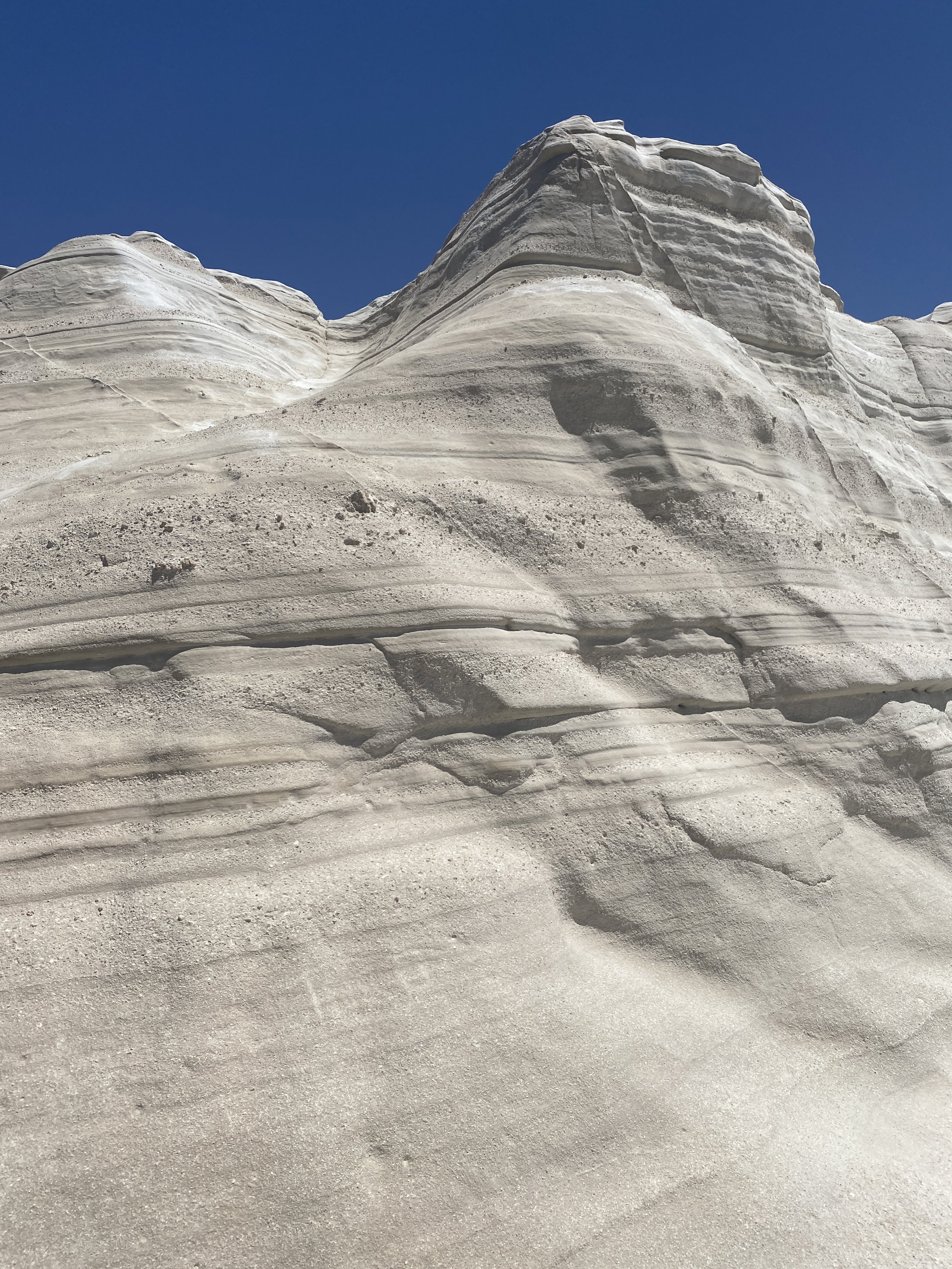 Close-up view of layered white sandstone formations under a clear blue sky.