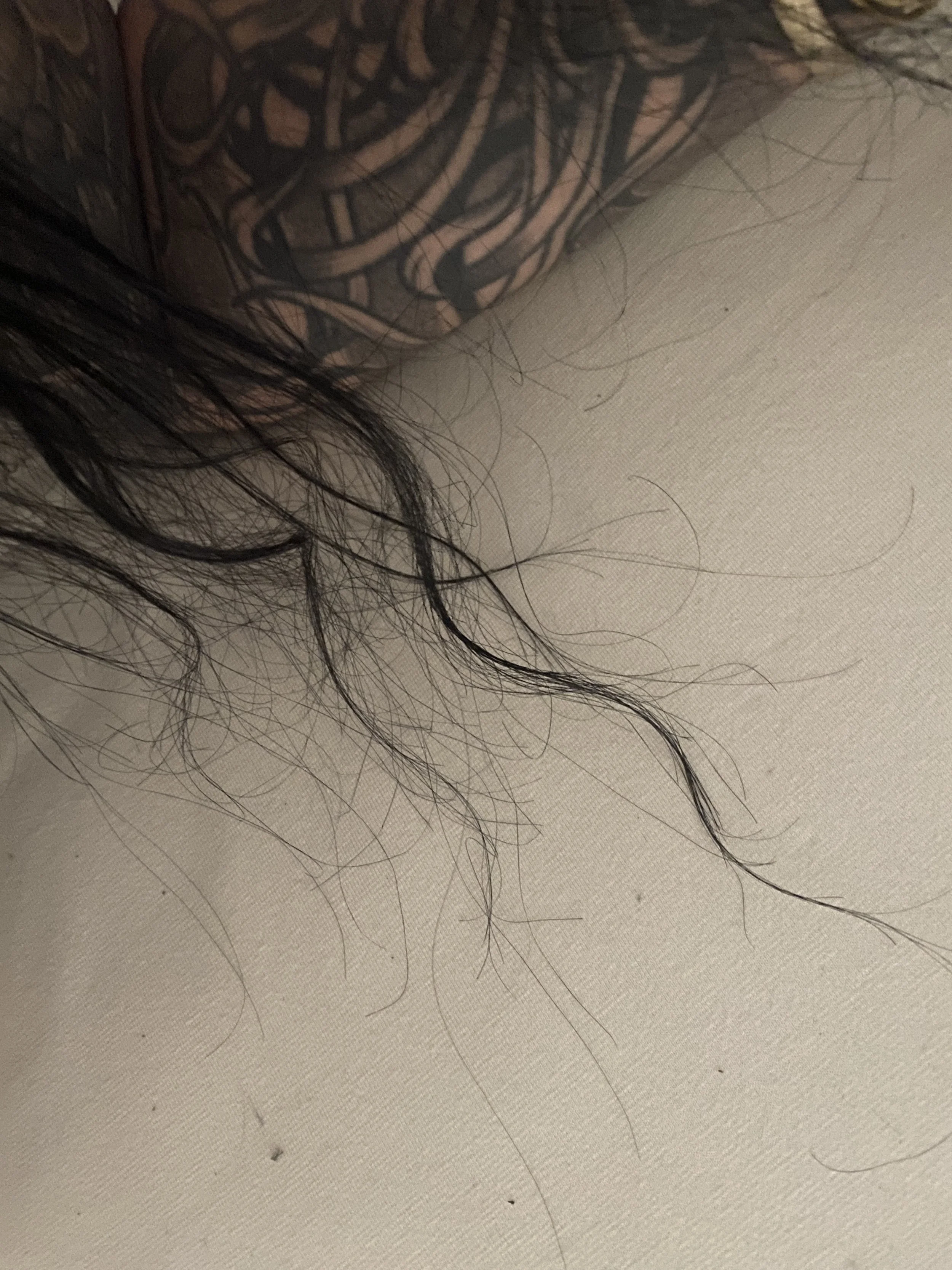 Close-up of dark, curly hair and part of a tattoo on skin