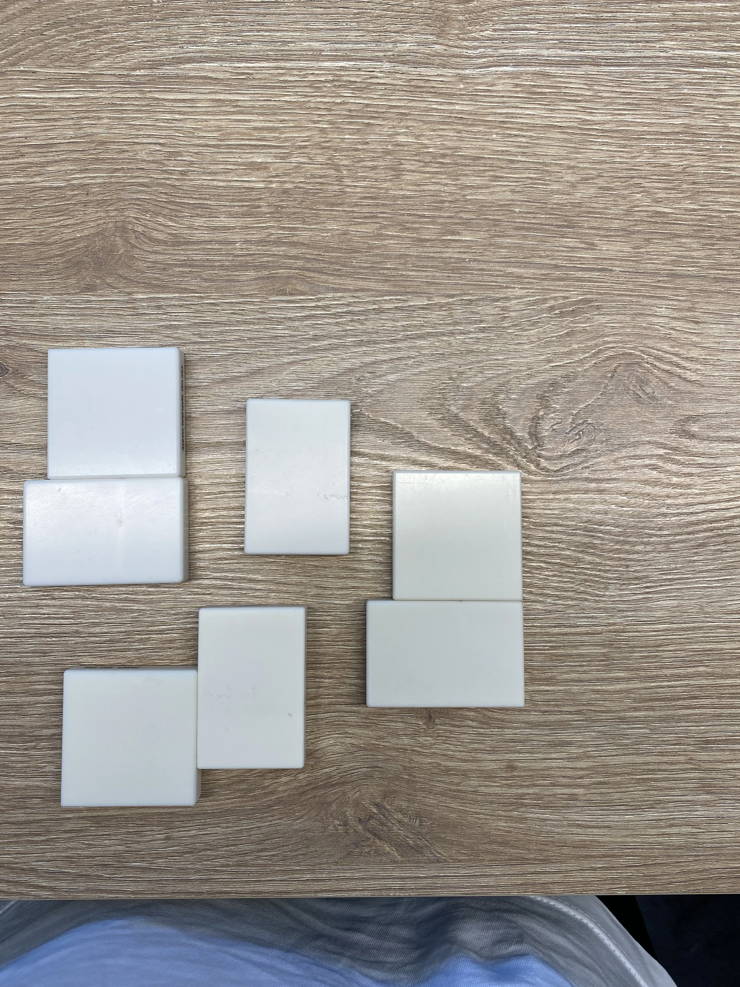 White rectangular tiles arranged on a wooden surface, forming a pattern.