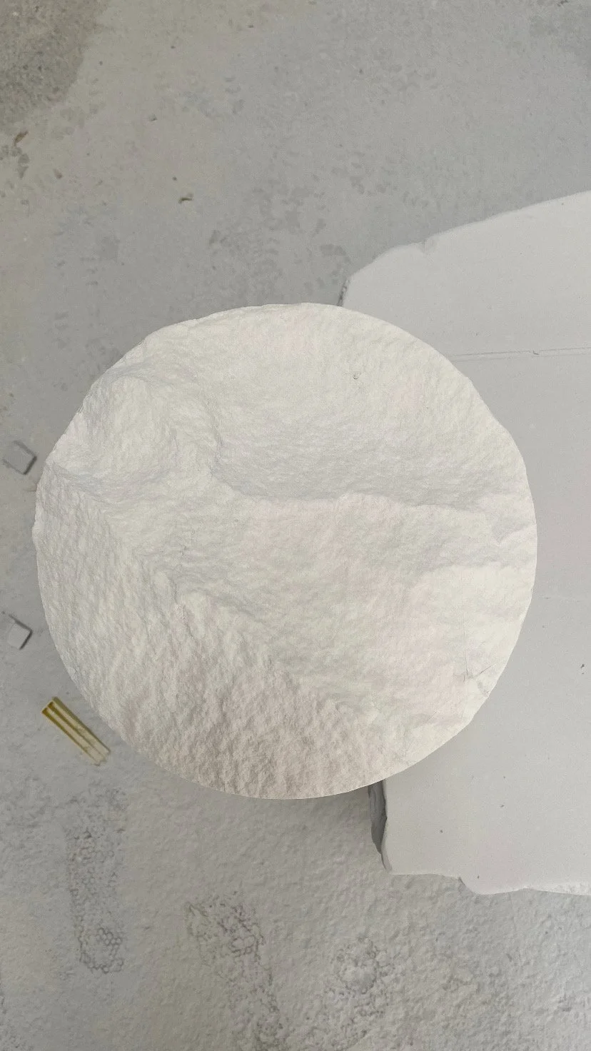 Close-up of a roll of white paper towels on a gray surface.