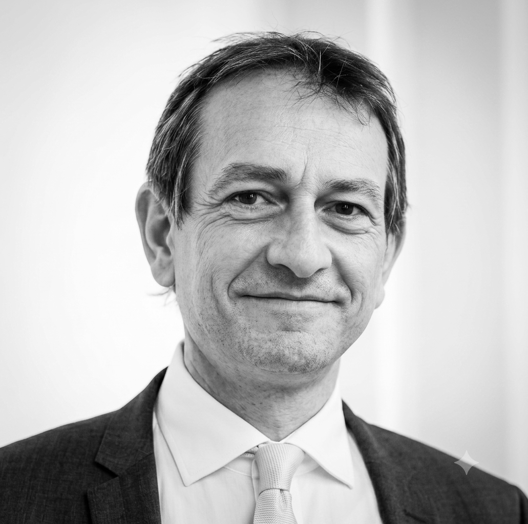 Black and white photo of a middle-aged man wearing a suit, tie, and dress shirt, smiling at the camera.