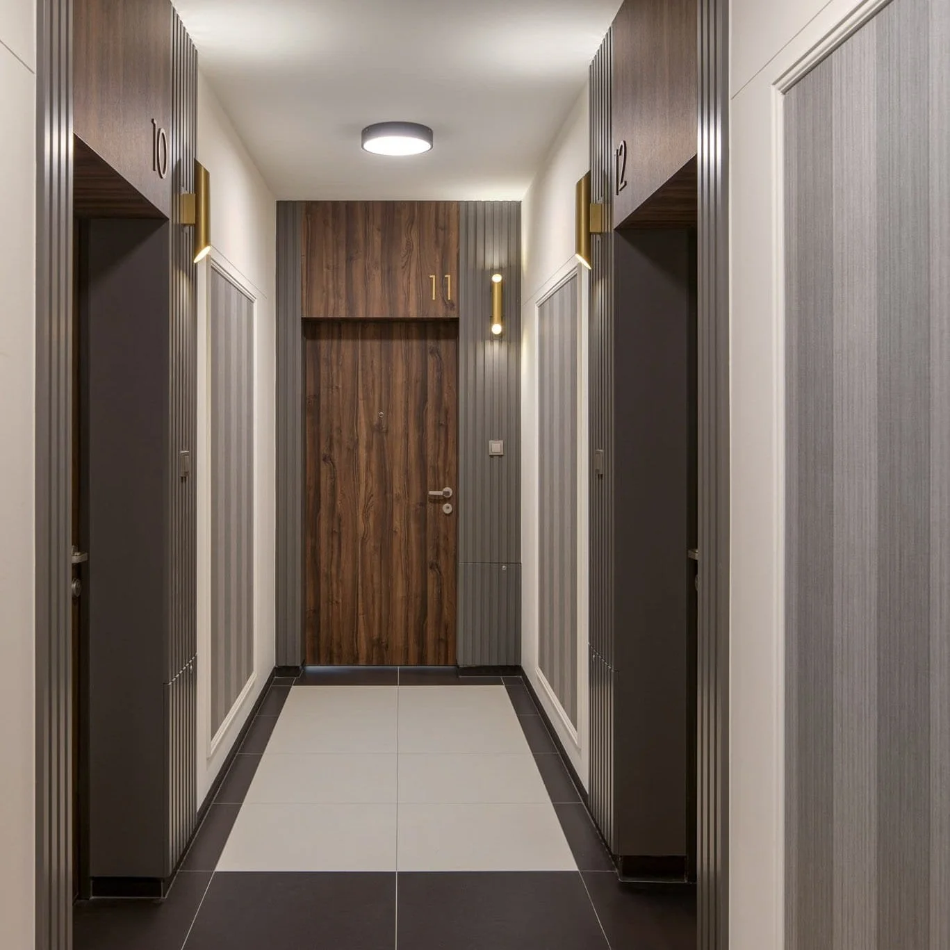 Hallway with elevator doors, grey textured walls, a wooden door at the end with the number 11, modern wall-mounted lights, and a tiled floor.