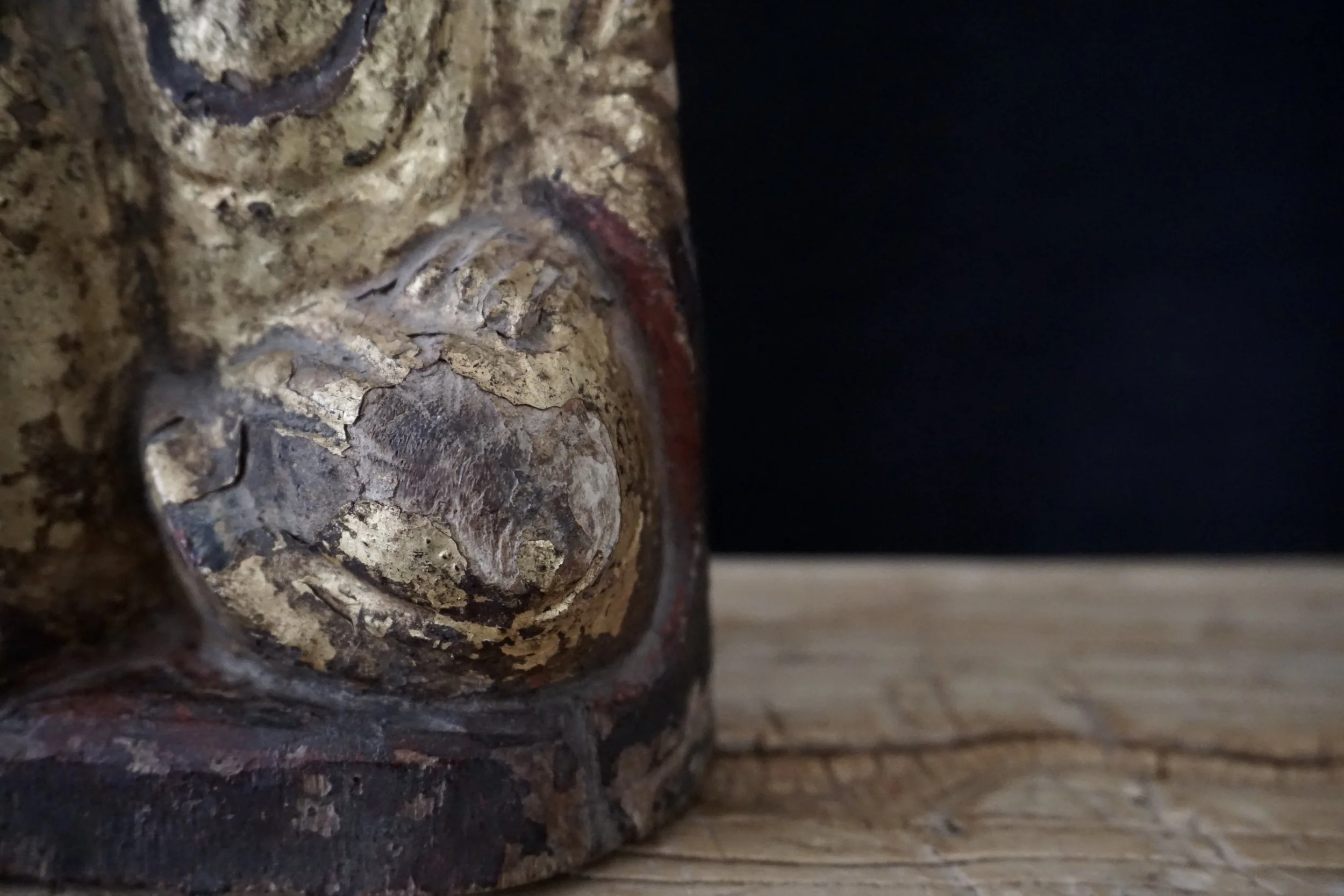 Détail d'une sculpture en bois avec une finition ancienne, montrant une partie d'un visage sculpté.