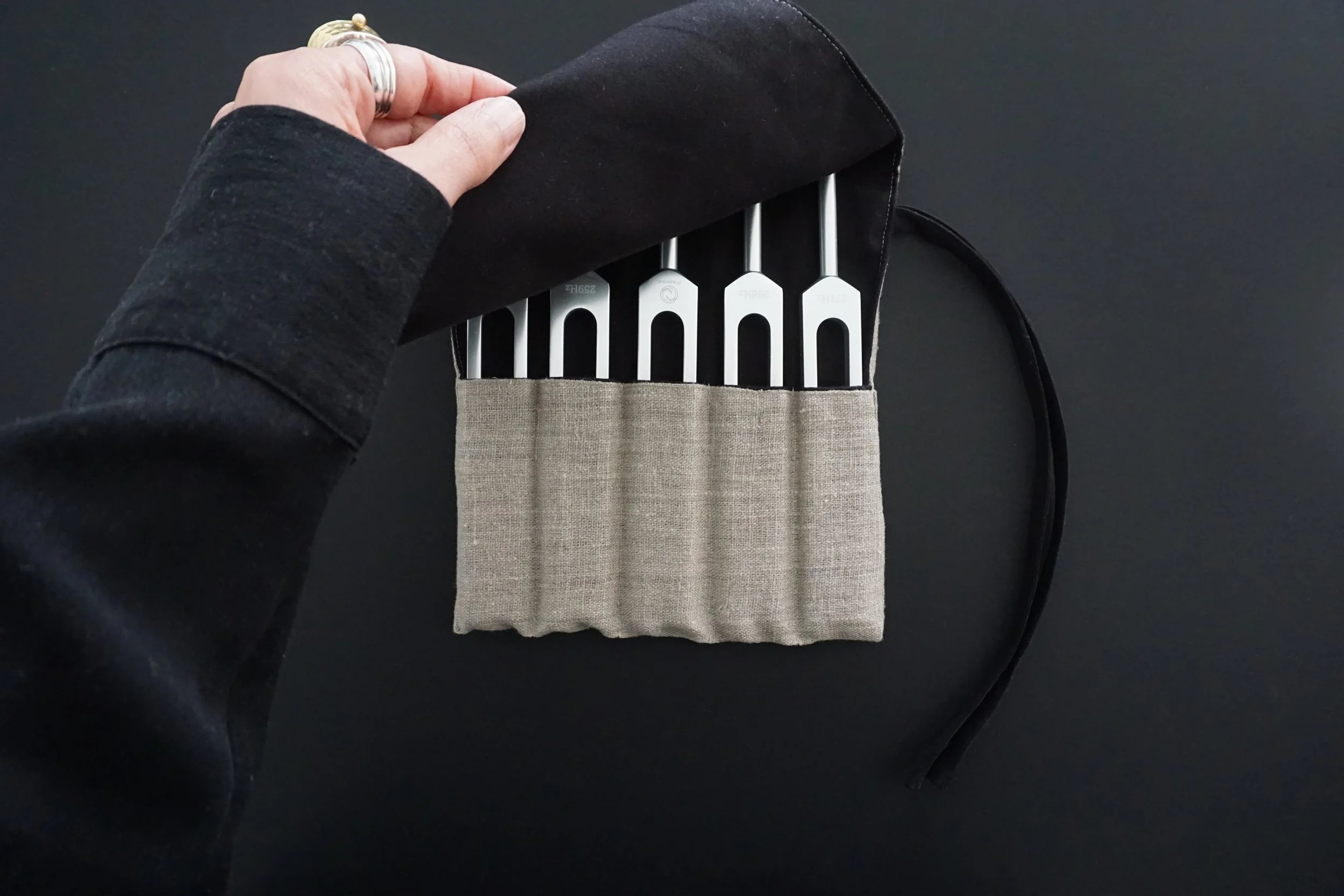 Une main tenant un étui en tissu contenant des clés, sur un fond noir.